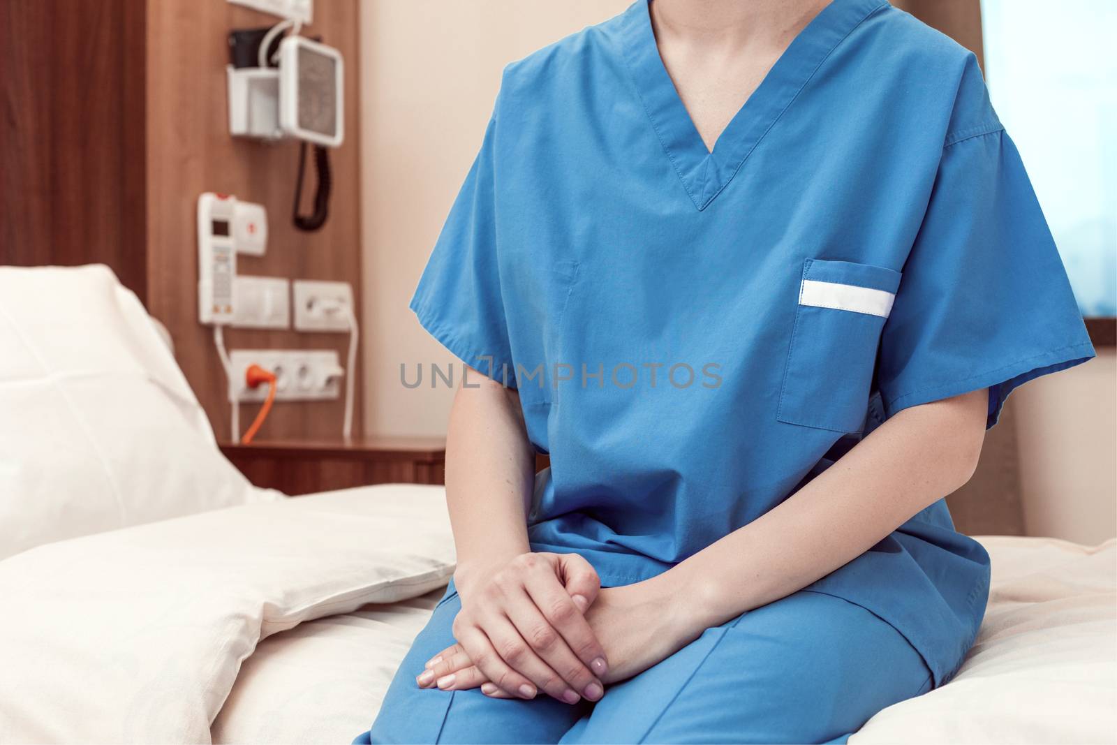 A patient sitting on a hospital bed with hands resting in his lap.