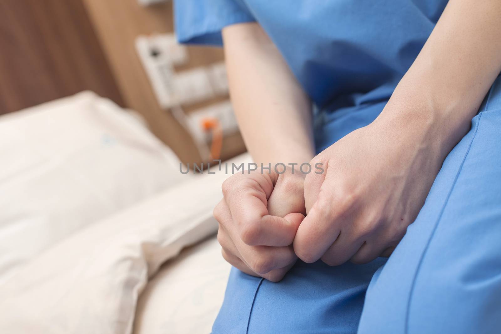 A patient's hands squeezing thumbs with hope in a modern hospital.