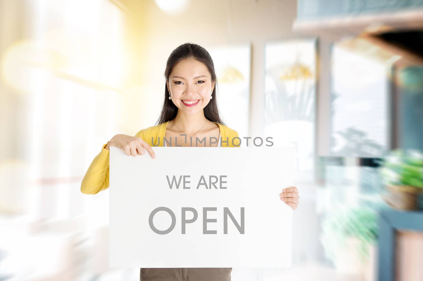 Young Asian woman hand holding "we are open" sign board in restaurant or cafe. 