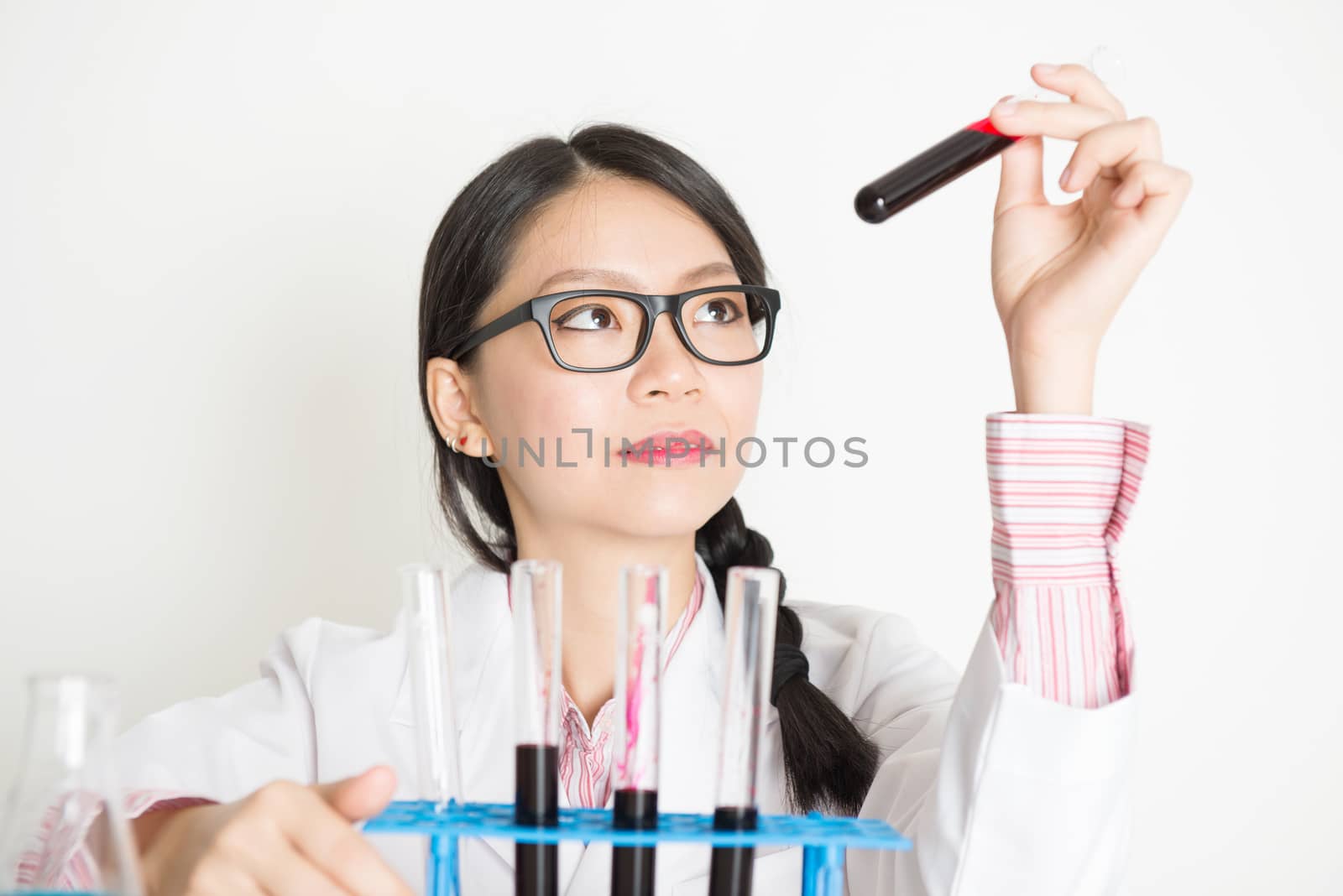 Young attractive Asian laboratory assistant checking the blood in tube, portrait shot of a female scientist.