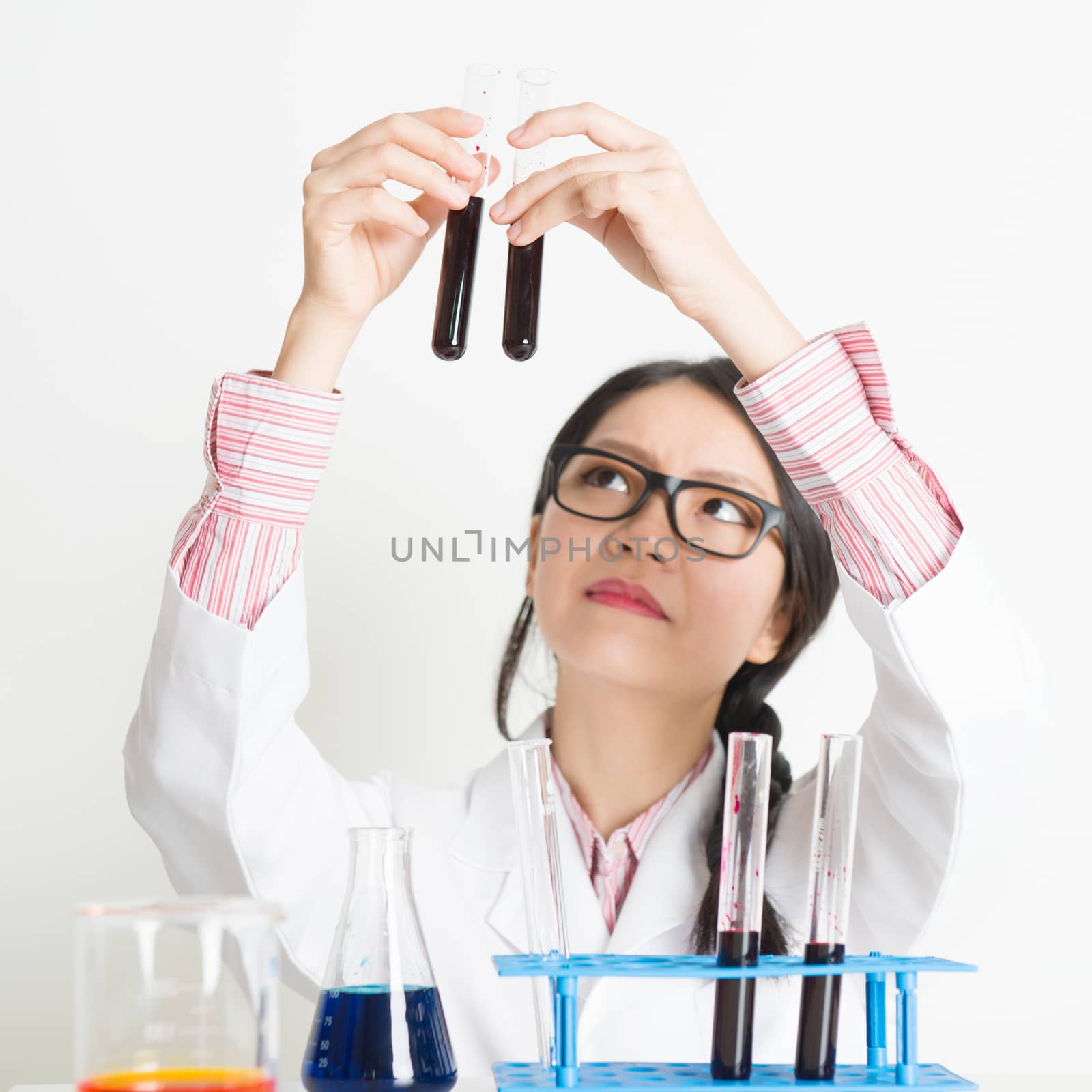 Young Asian female lab assistant looking at the tube in laboratory.