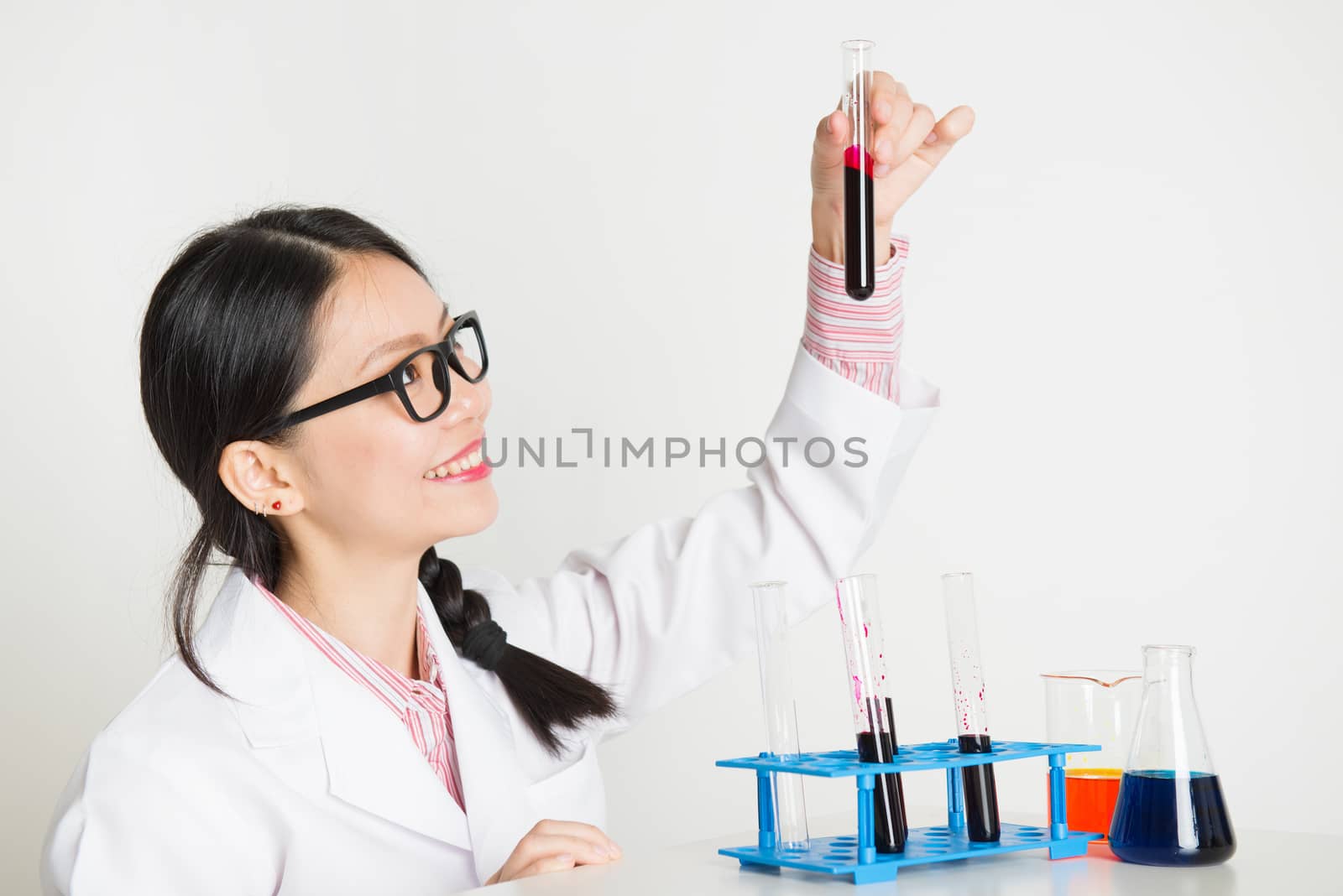 Attractive young Asian female researcher looking at the tube in laboratory.