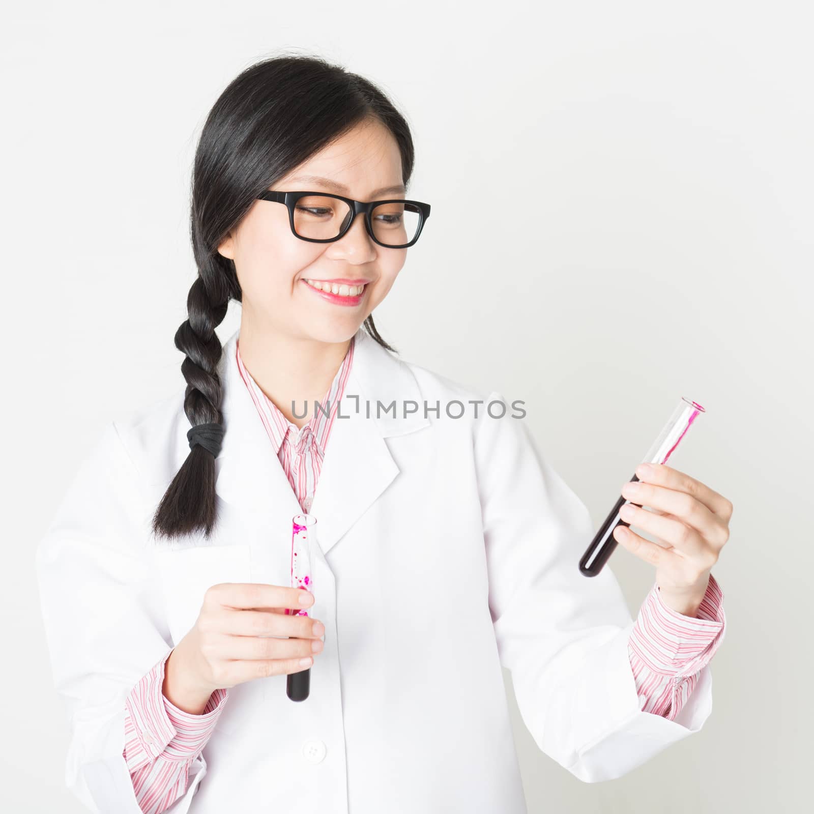 Young attractive laboratory assistant checking the blood in tube, portrait shot of a female scientist.