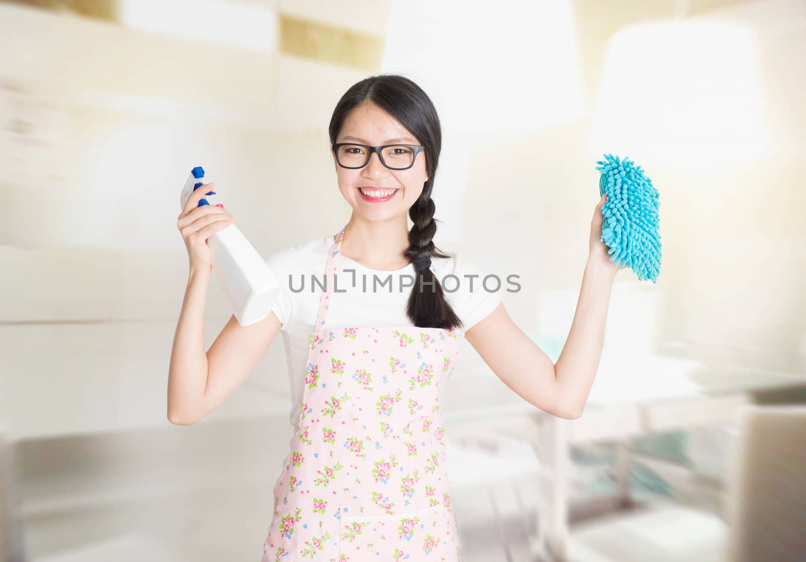 Young Asian woman preparing to clean the kitchen. Hand holding detergent spray and scrub.