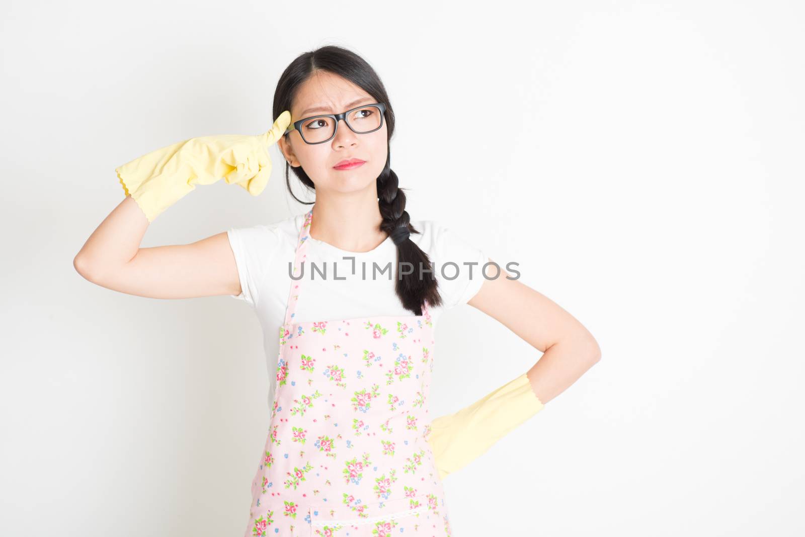Young Asian housewife thinking getting an idea before start to clean up her home.