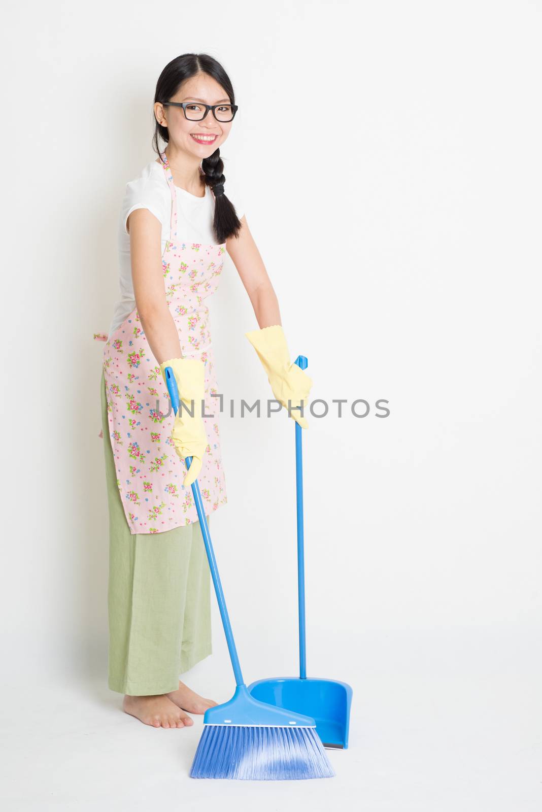 Young Asian housewife sweeping floor with broom and dustpan , cleaning floor.