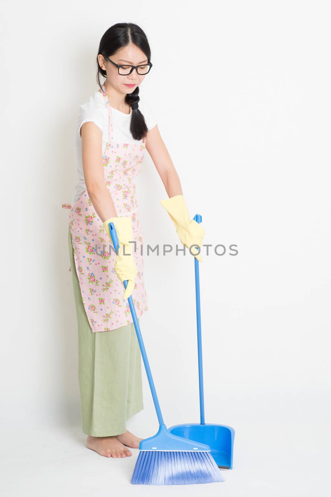 Young Asian woman sweeping floor with broom and dustpan , cleaning floor.