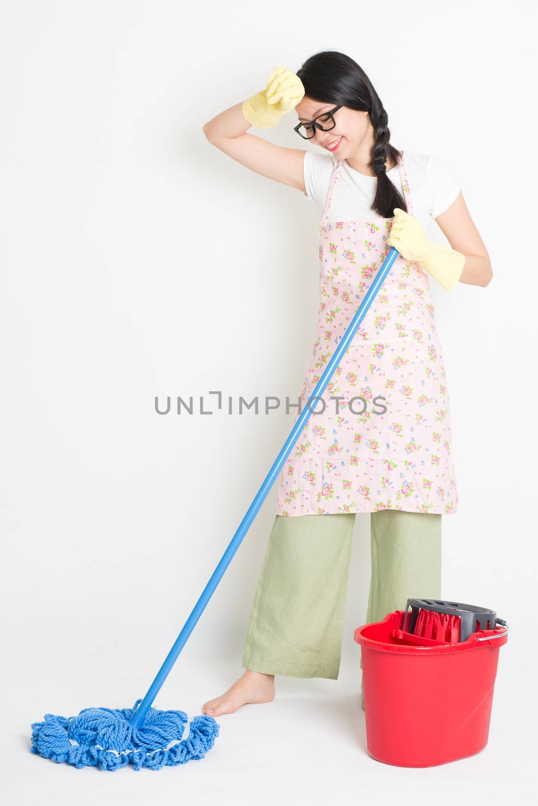 Young Asian girl mopping floor with water, cleaning house.