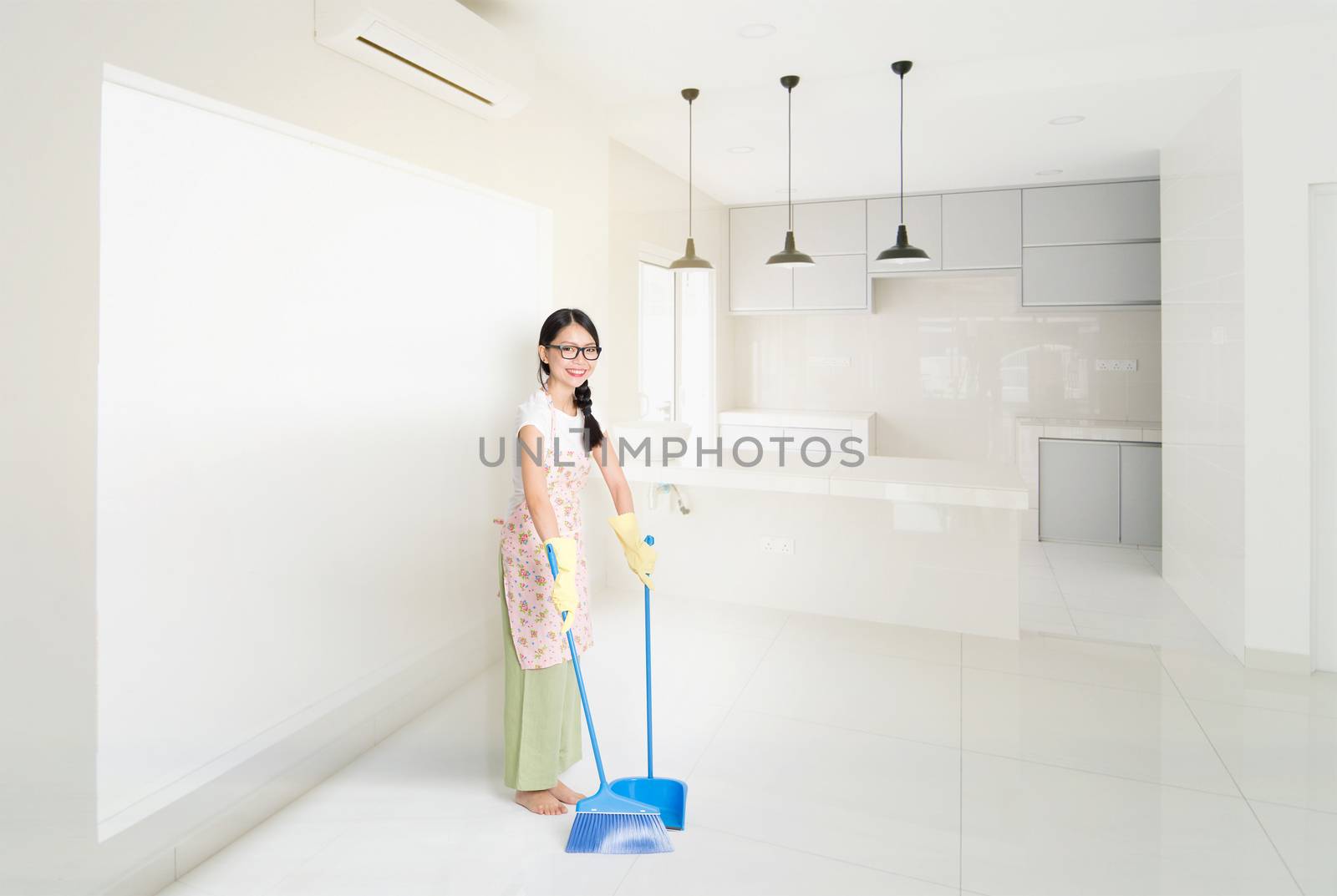 Young Asian housewife sweeping floor with broom and dustpan , cleaning house.