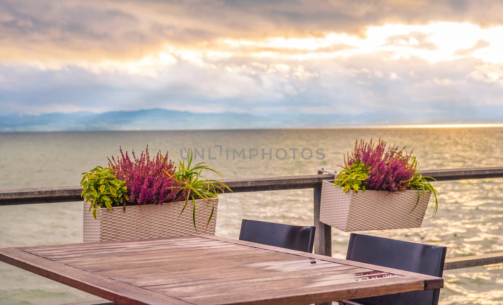 Conceptual image with an empty table, on a terrace, on the shore of the Bodensee lake, at sunset.