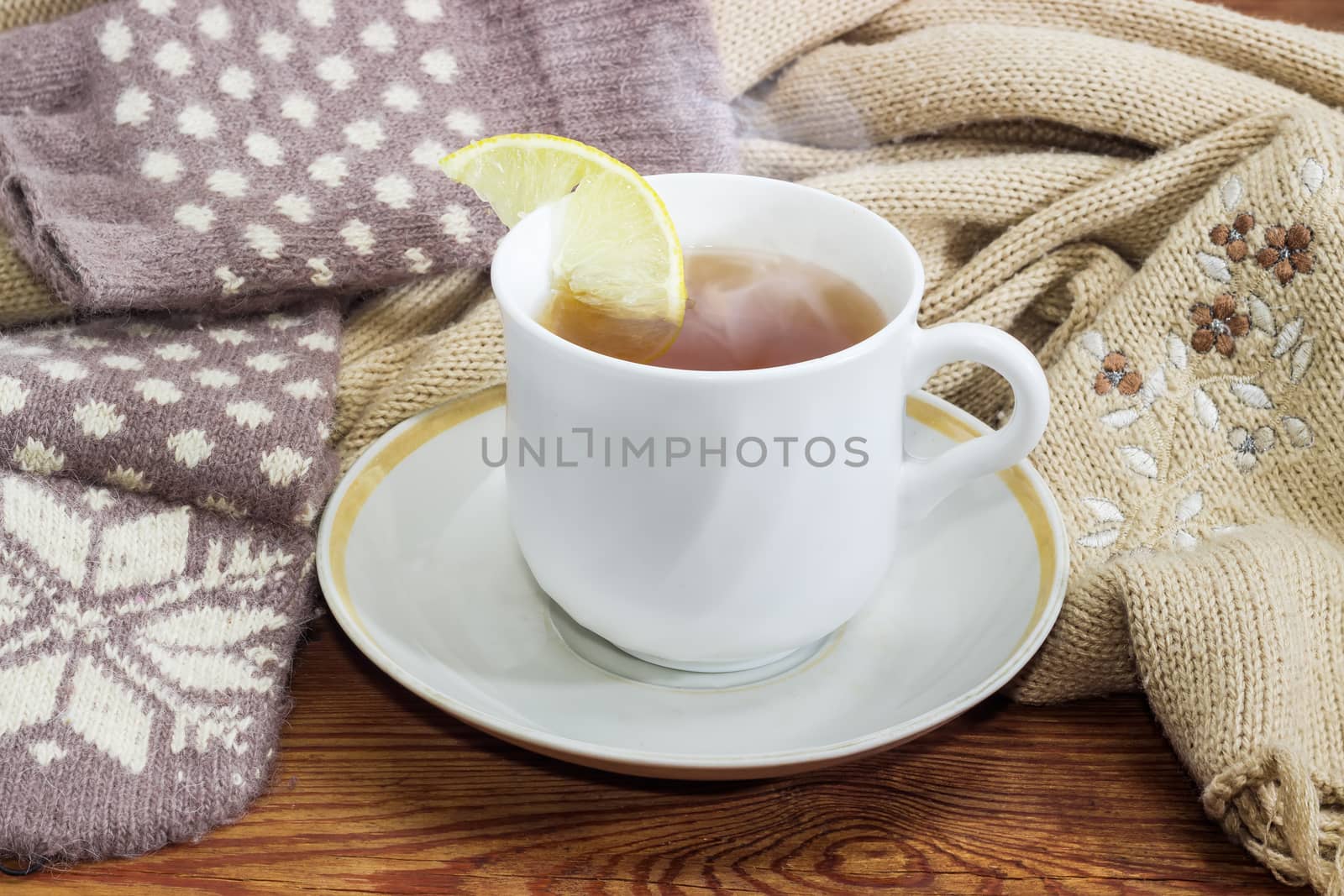 Cup of tea on background of woolen mittens and scarf by anmbph