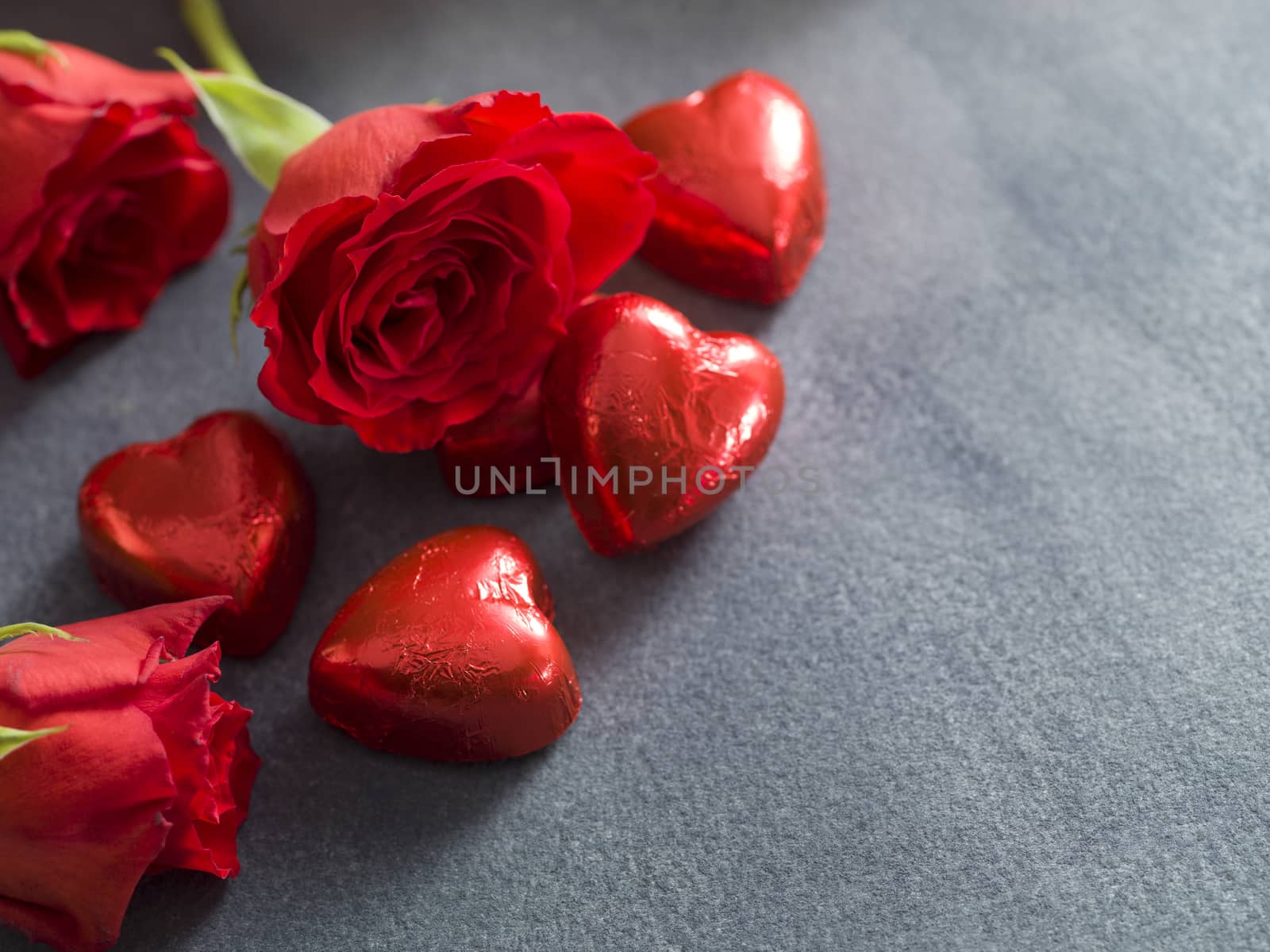 Chocolate hearts and red roses on a grey background. Valentines day background
