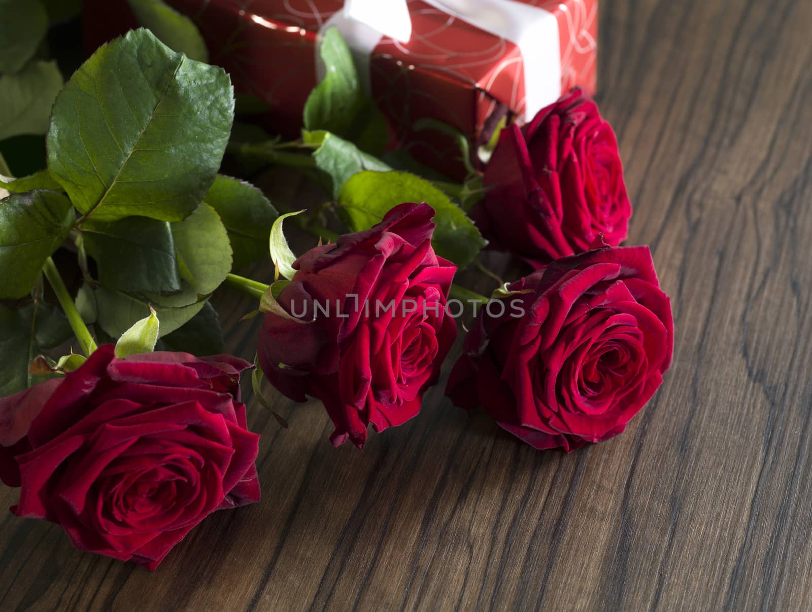 Gift box with a white ribbon and a red roses bouquet by janssenkruseproductions