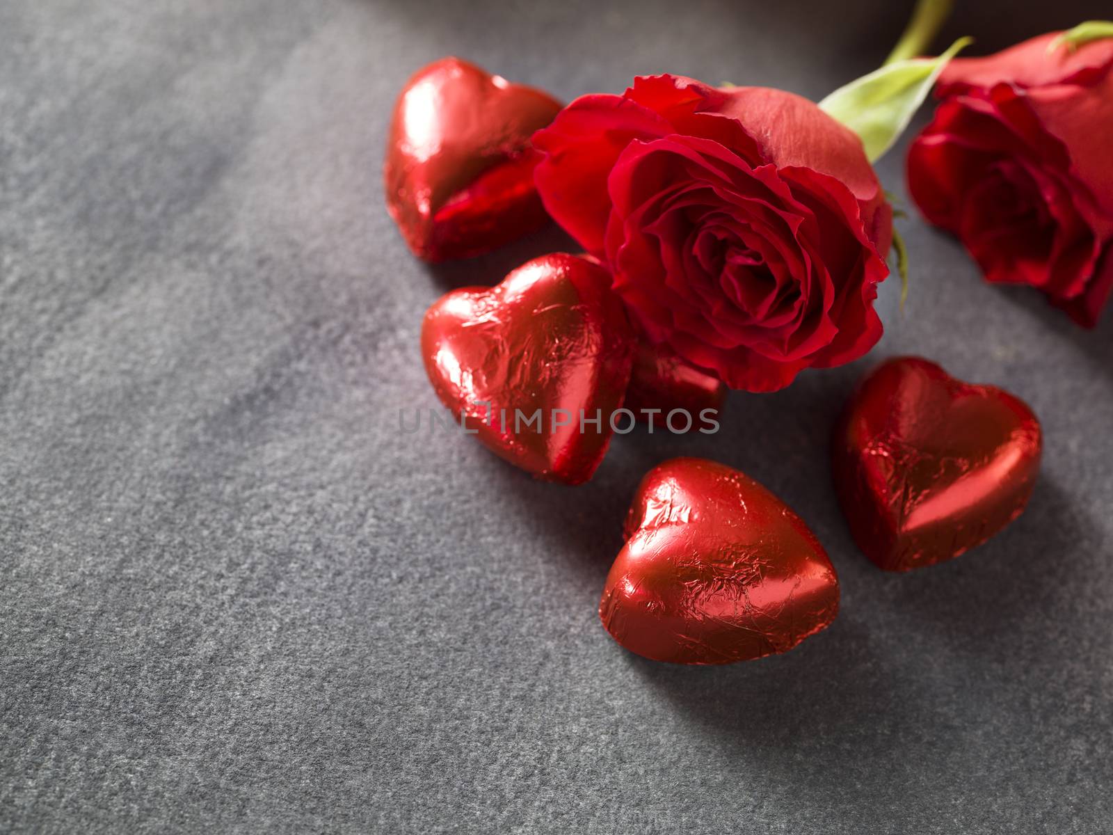 Red roses with chocolate hearts on a grey background. weddings day background