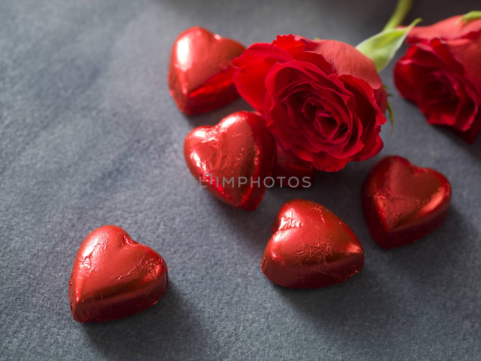 Valentines day background with chocolate hearts and red roses by janssenkruseproductions