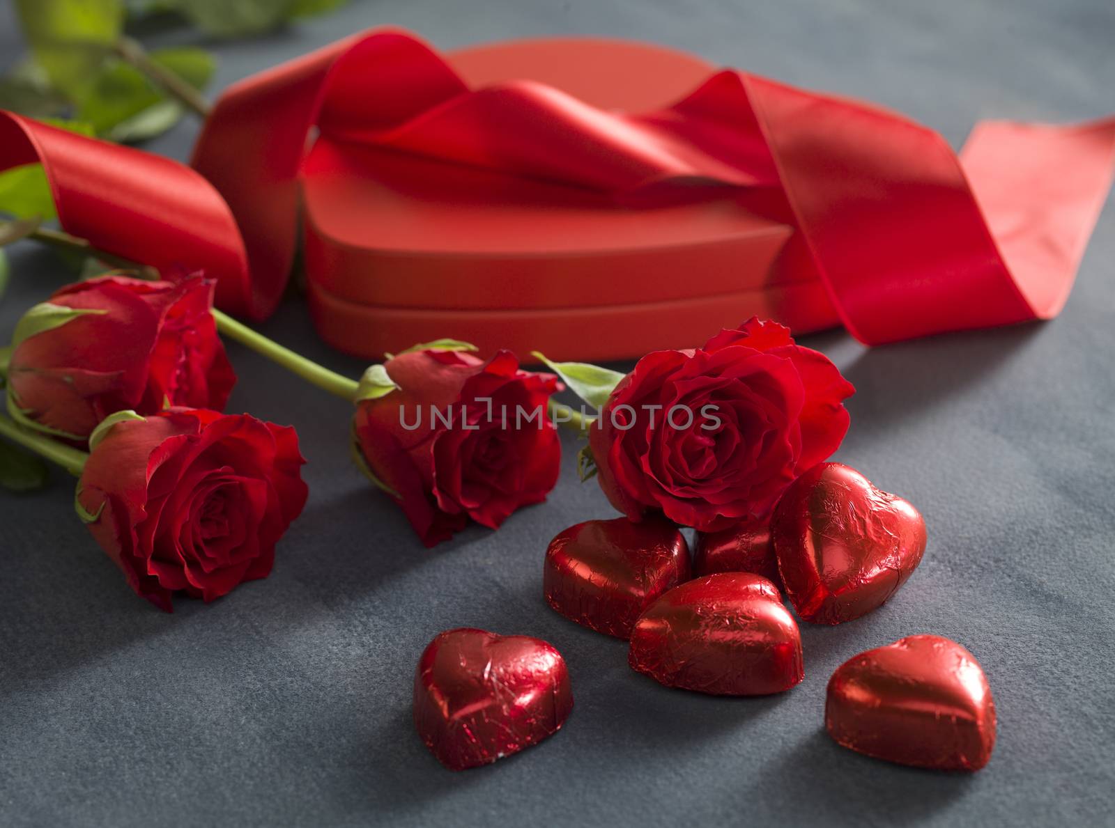 red hearts chocolates in front of red roses and hart shaped box. Valentines Day concept