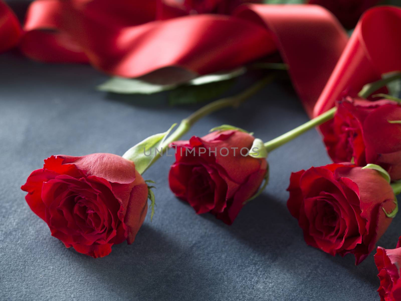 close up from fresh red roses and red ribbon on grey blue paper. Wedding concept
