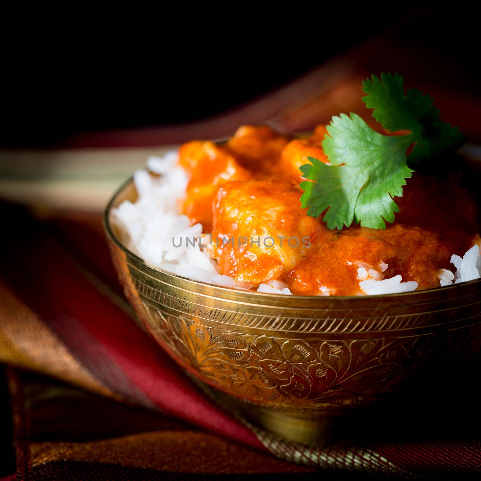 Bowl of spicy indian butter chicken in white basmati rice.