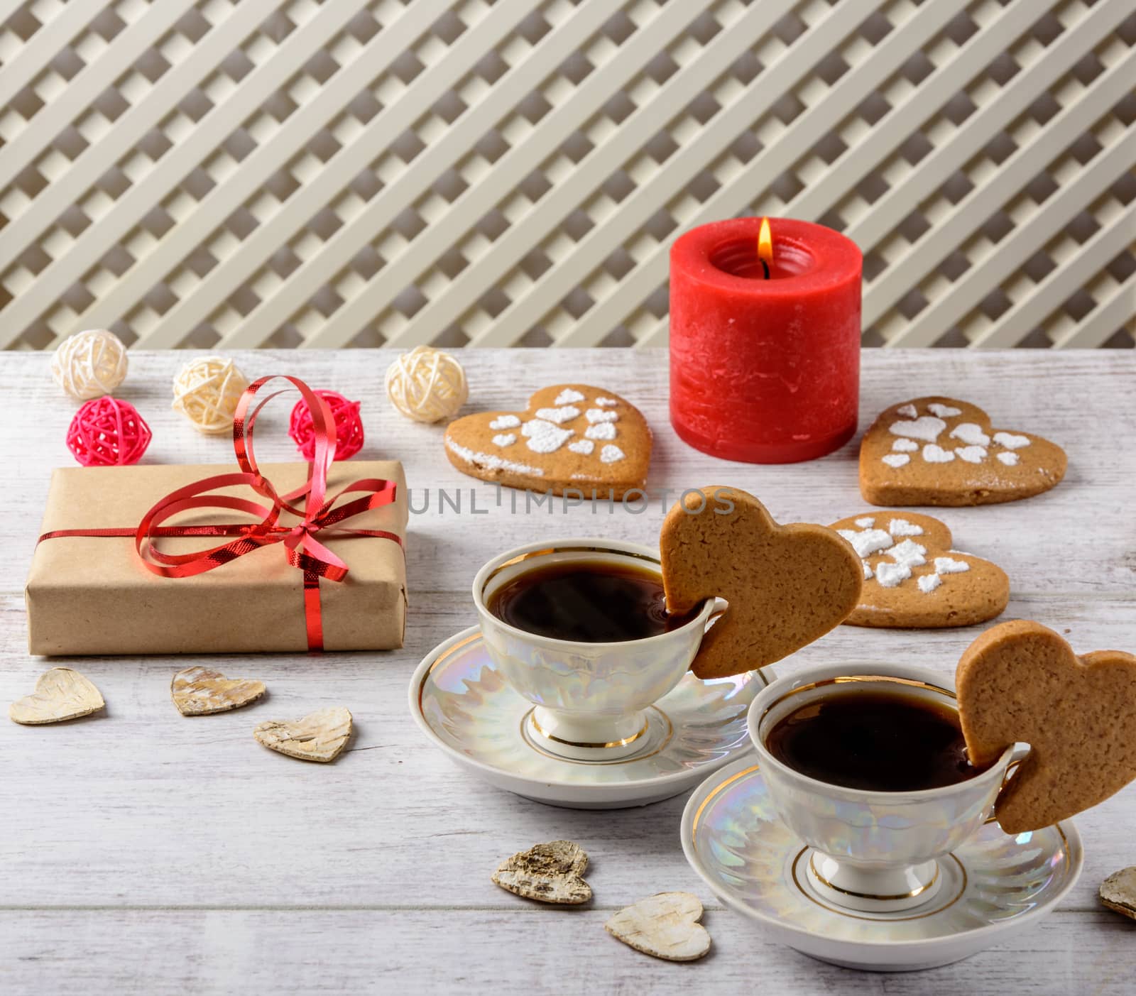 Box with a present to the Valentine's Day cookies in the shape of a heart and cups of black coffee on the white table