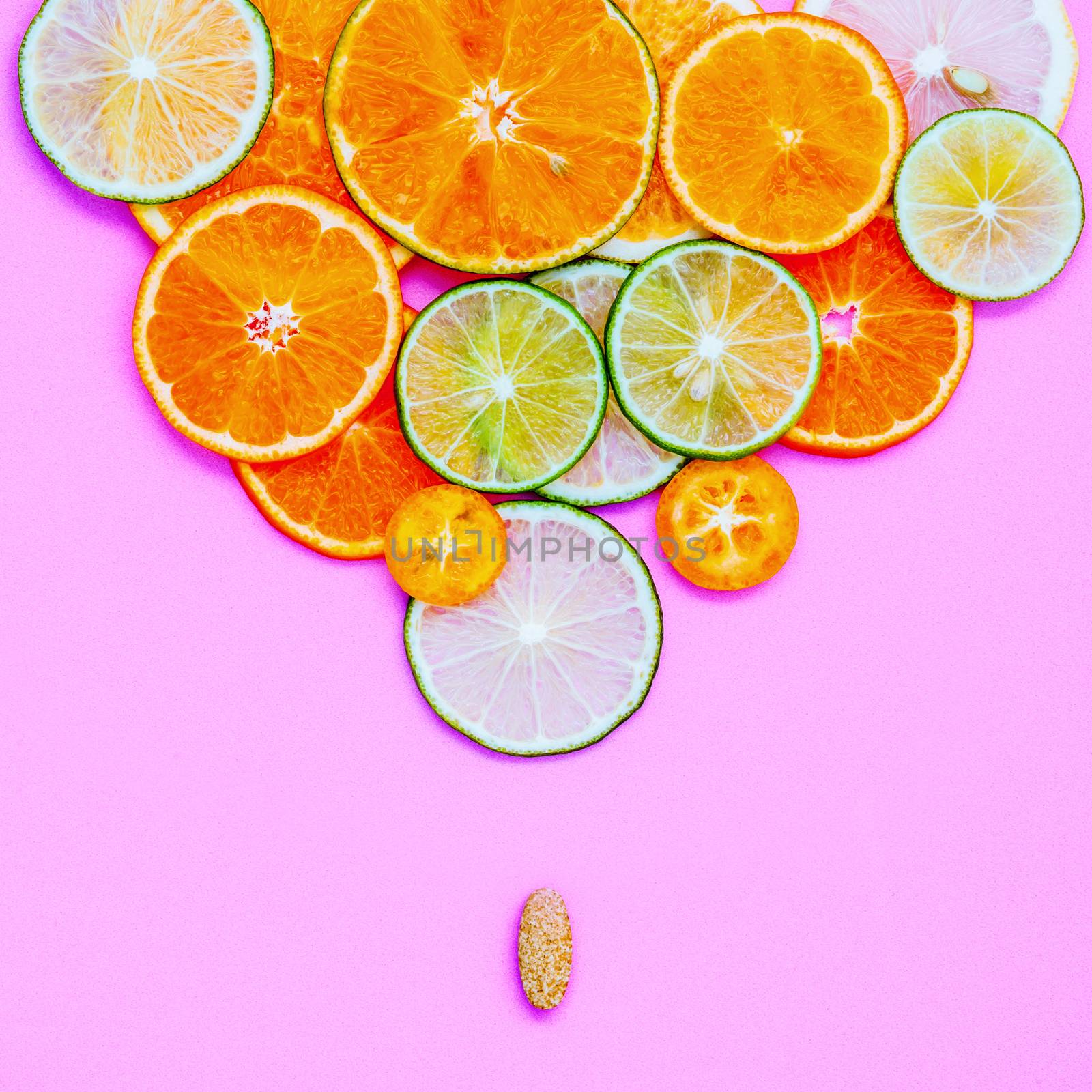 Healthy foods and medicine concept. Pill of vitamin C and various citrus fruits. Citrus fruits sliced lime,orange ,kumquat and lemon on light pink background flat lay.