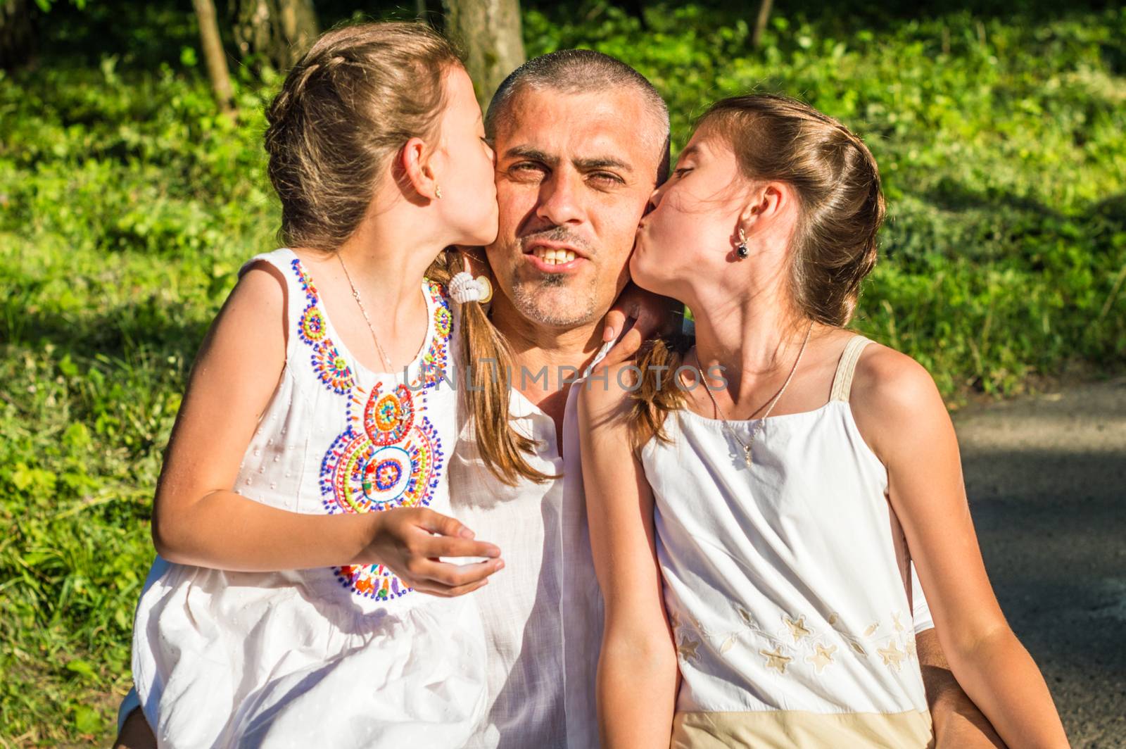 Daddy hugs his daughters in the Park