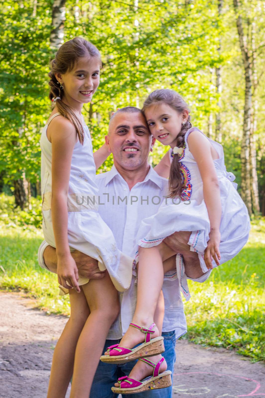 Daddy hugs his daughters in the Park