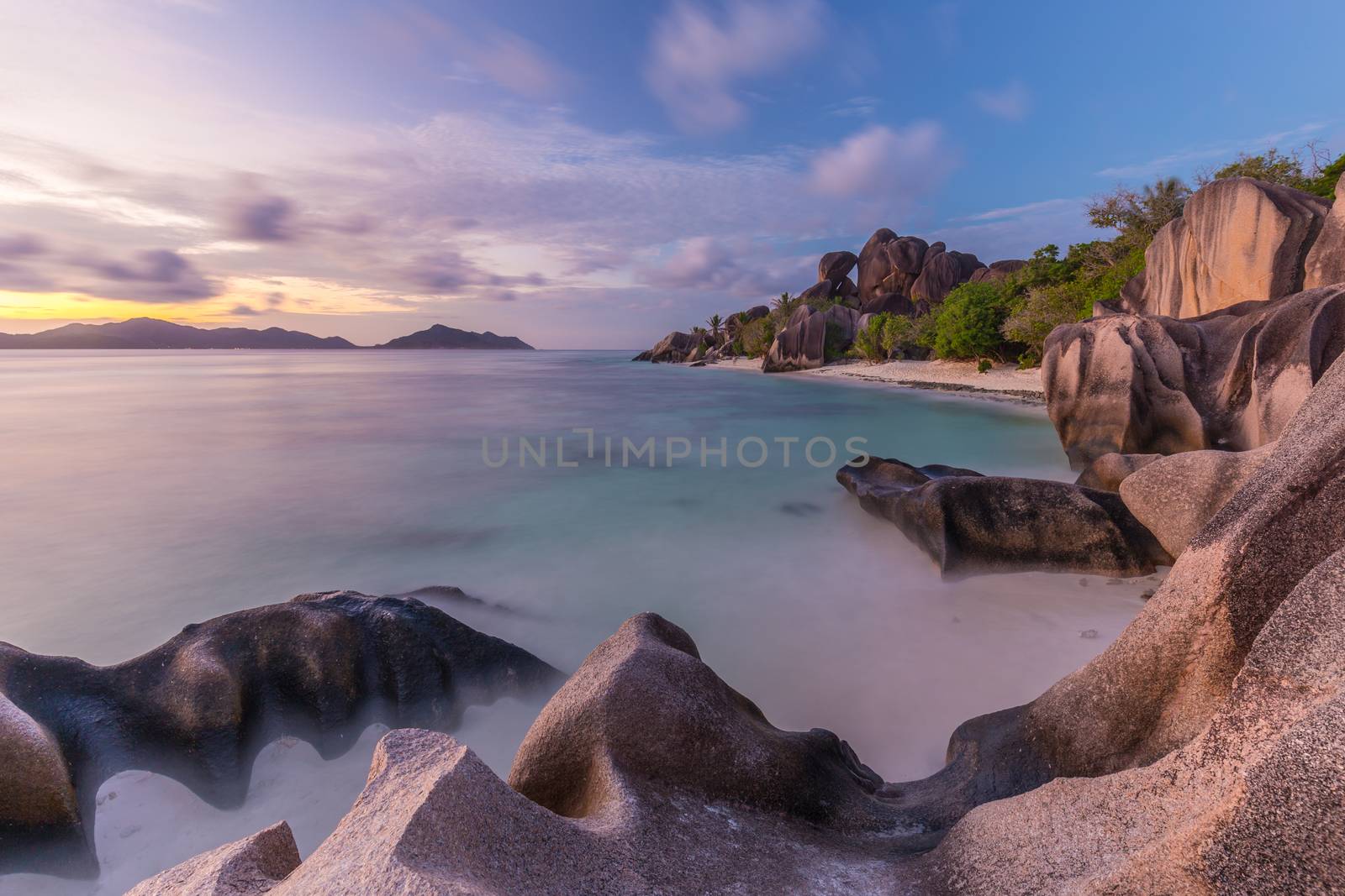 Beautifully shaped granite boulders and a dramatic sunset at picture perfect tropical Anse Source d'Argent beach, La Digue island, Seychelles.