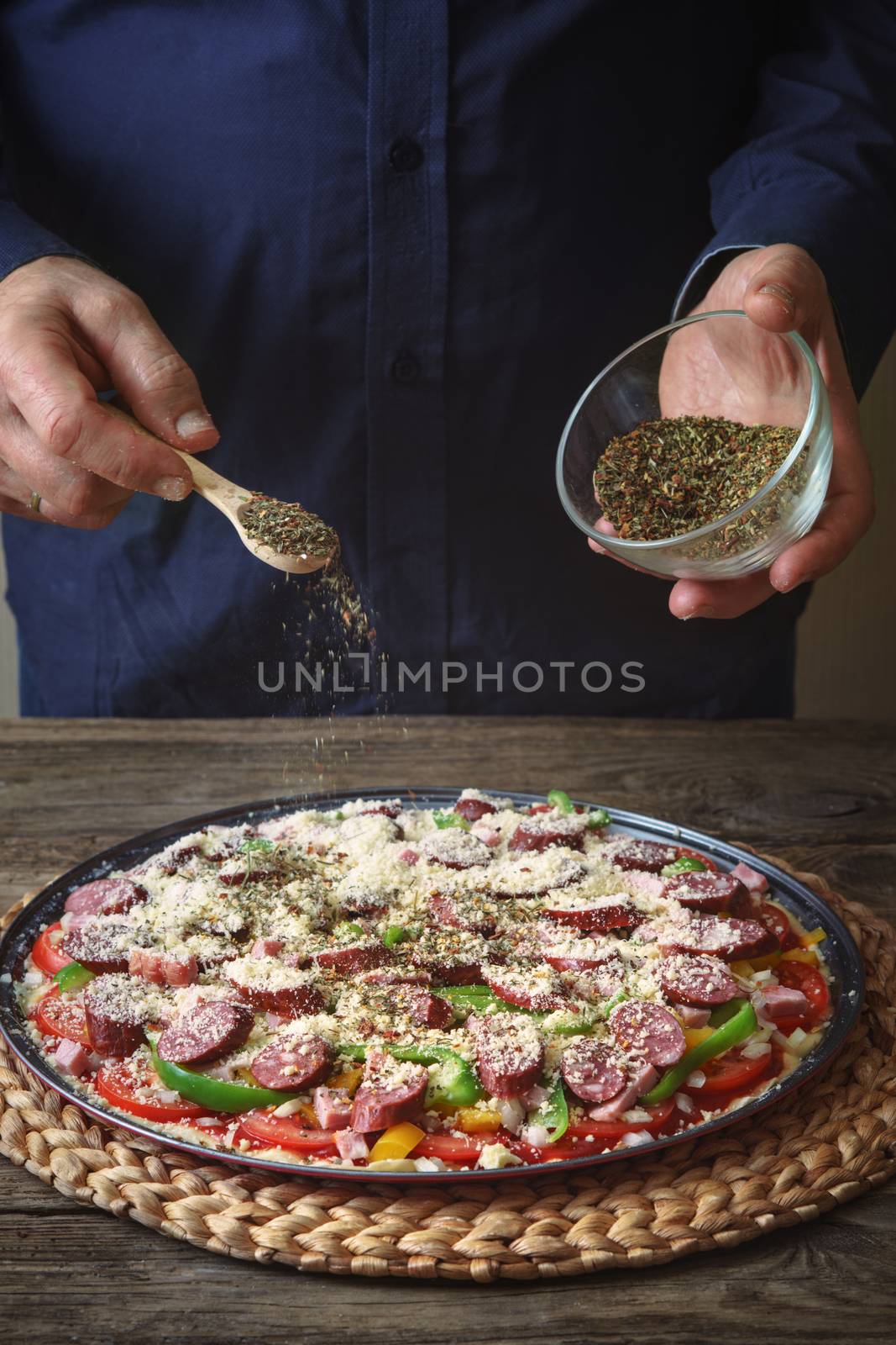 Man sprinkle with spice pizza from a glass sauser vertical