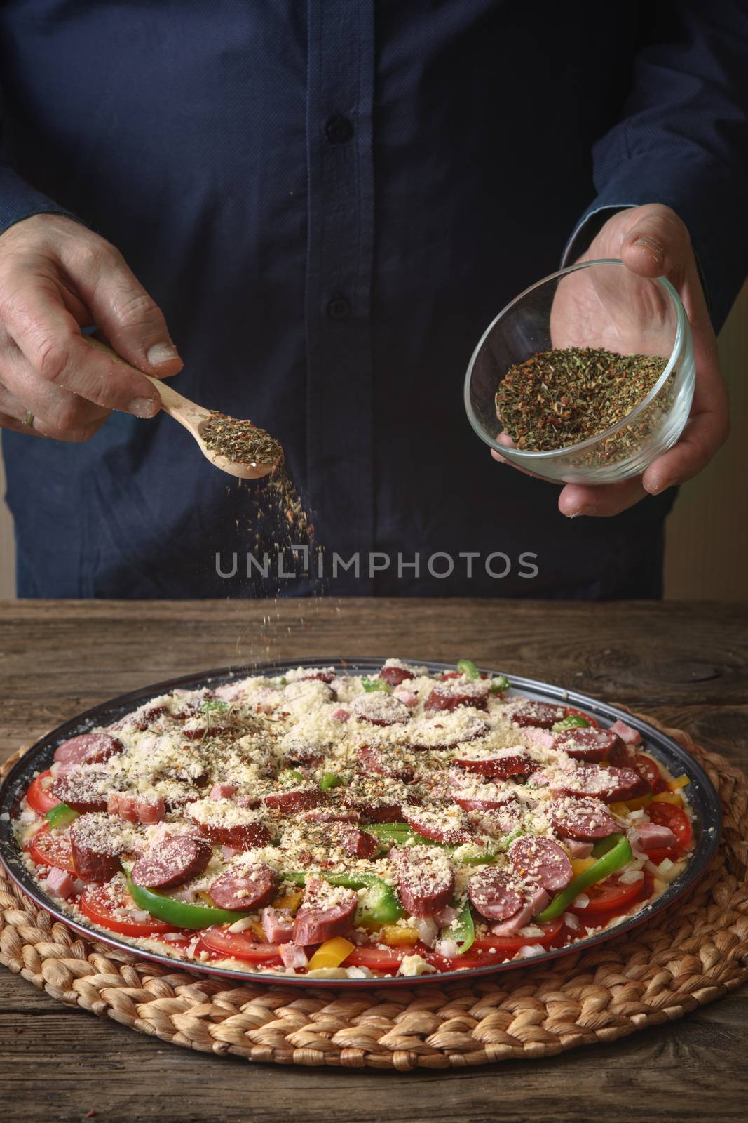 Man sprinkle with spice pizza from a glass sauser by Deniskarpenkov