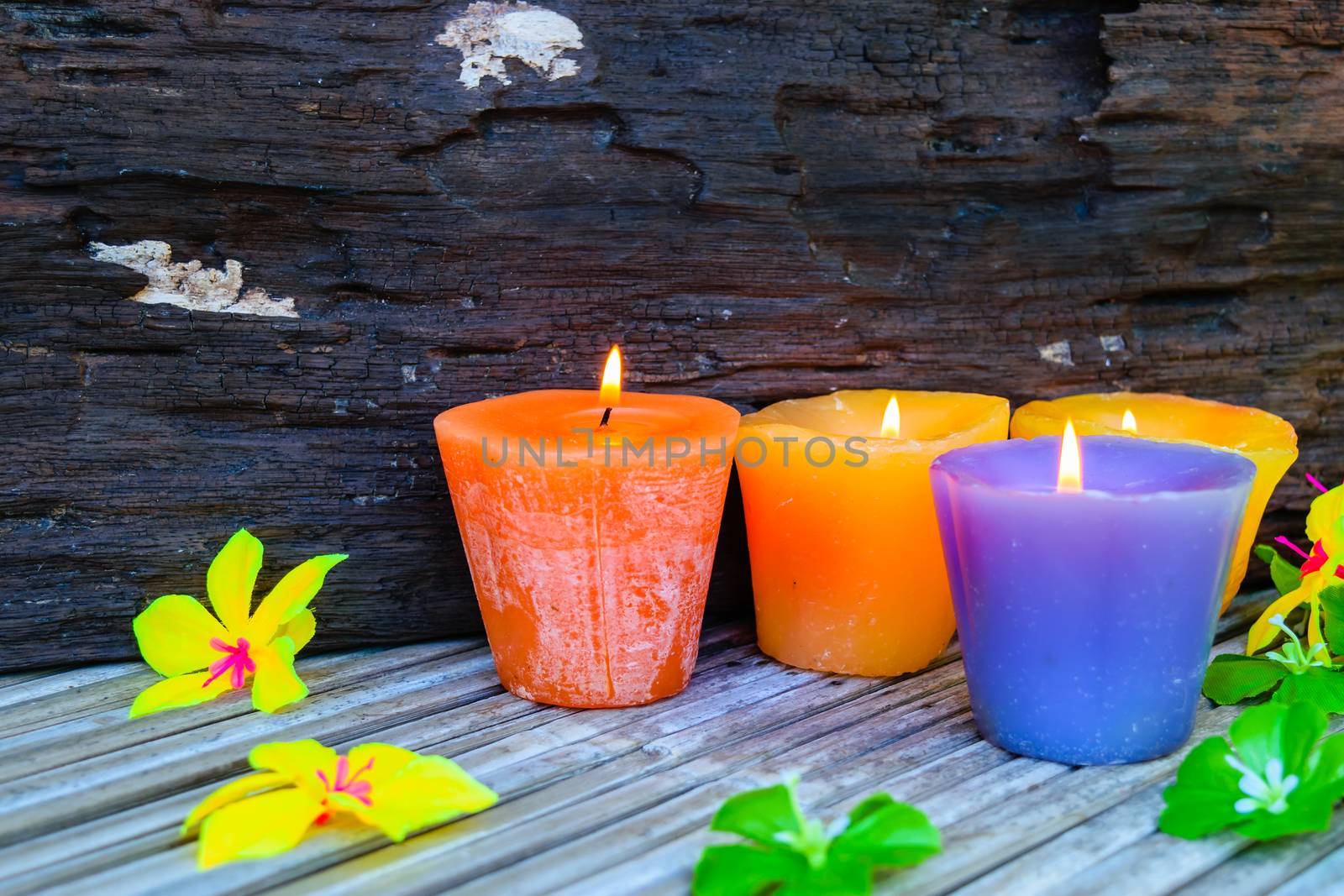 candles and flowers plastic beautiful on bamboo table on old wood background