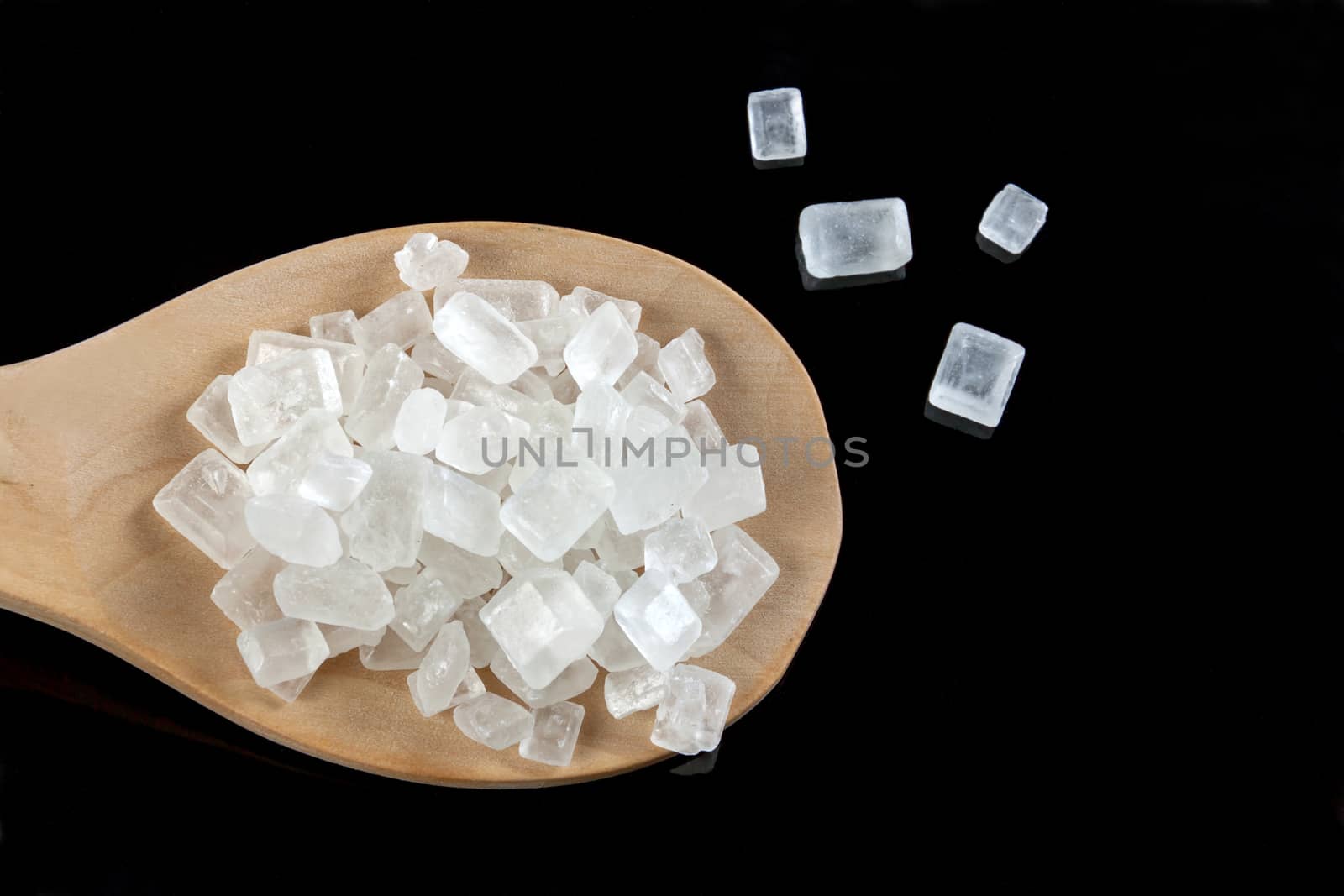 rock sugar white in a wooden spoon on the black background. Pure cane sugar for natural. no additives.