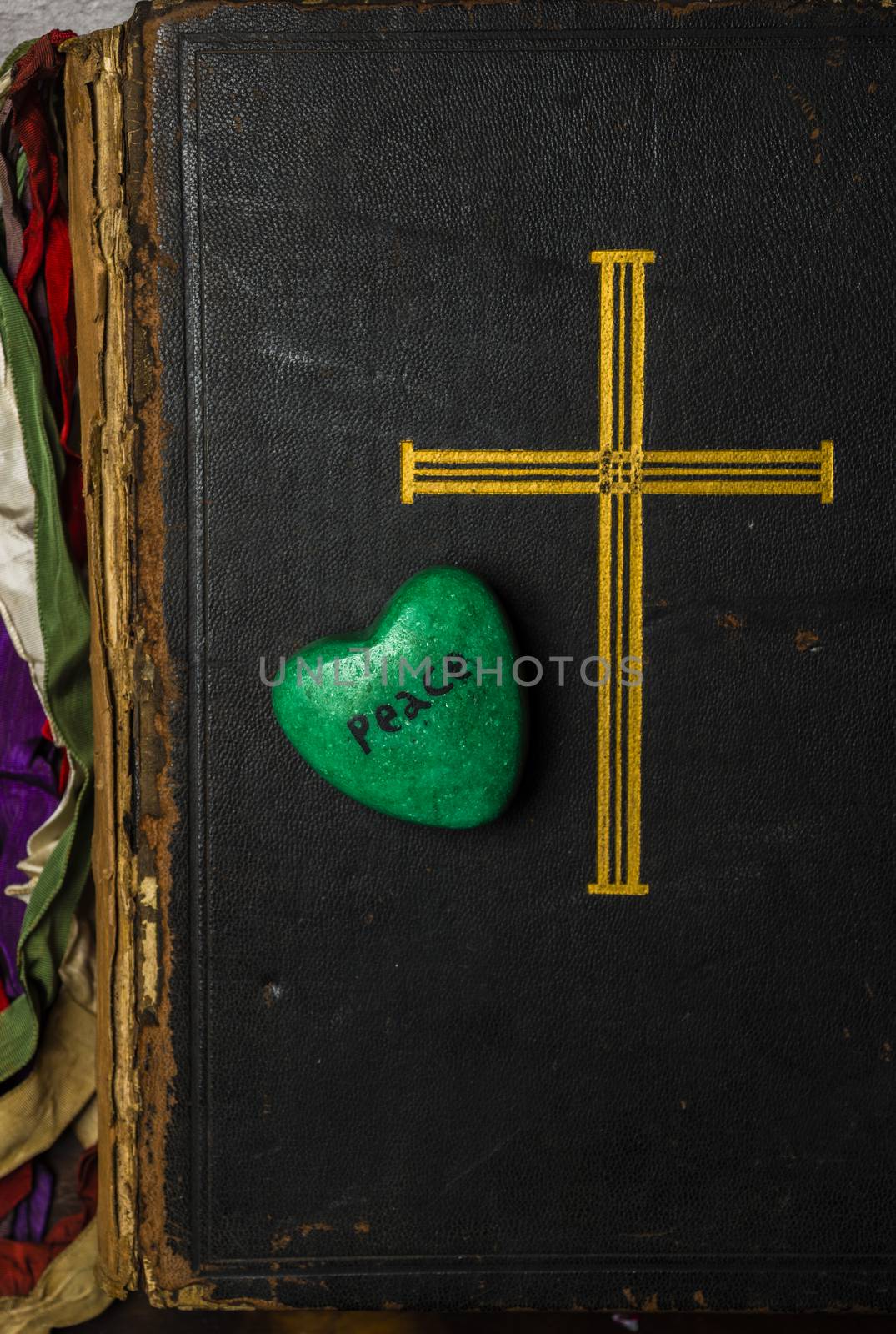 Catholic religion and peace concept represented by an old bible cover and a green - hope - heart.