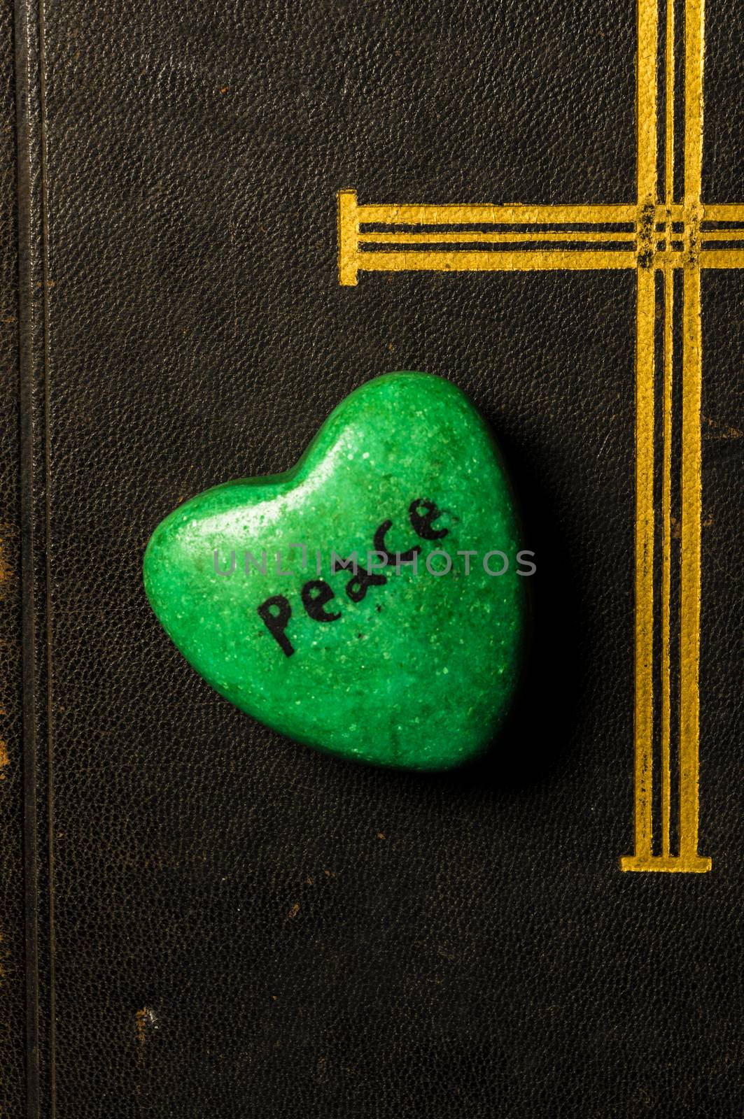 Catholic religion and peace concept represented by an old bible cover and a green - hope - heart.