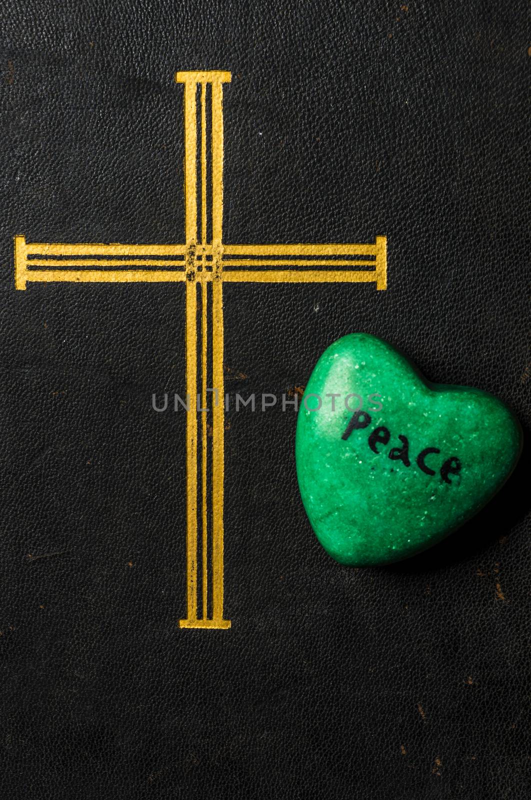 Catholic religion and peace concept represented by an old bible cover and a green - hope - heart.