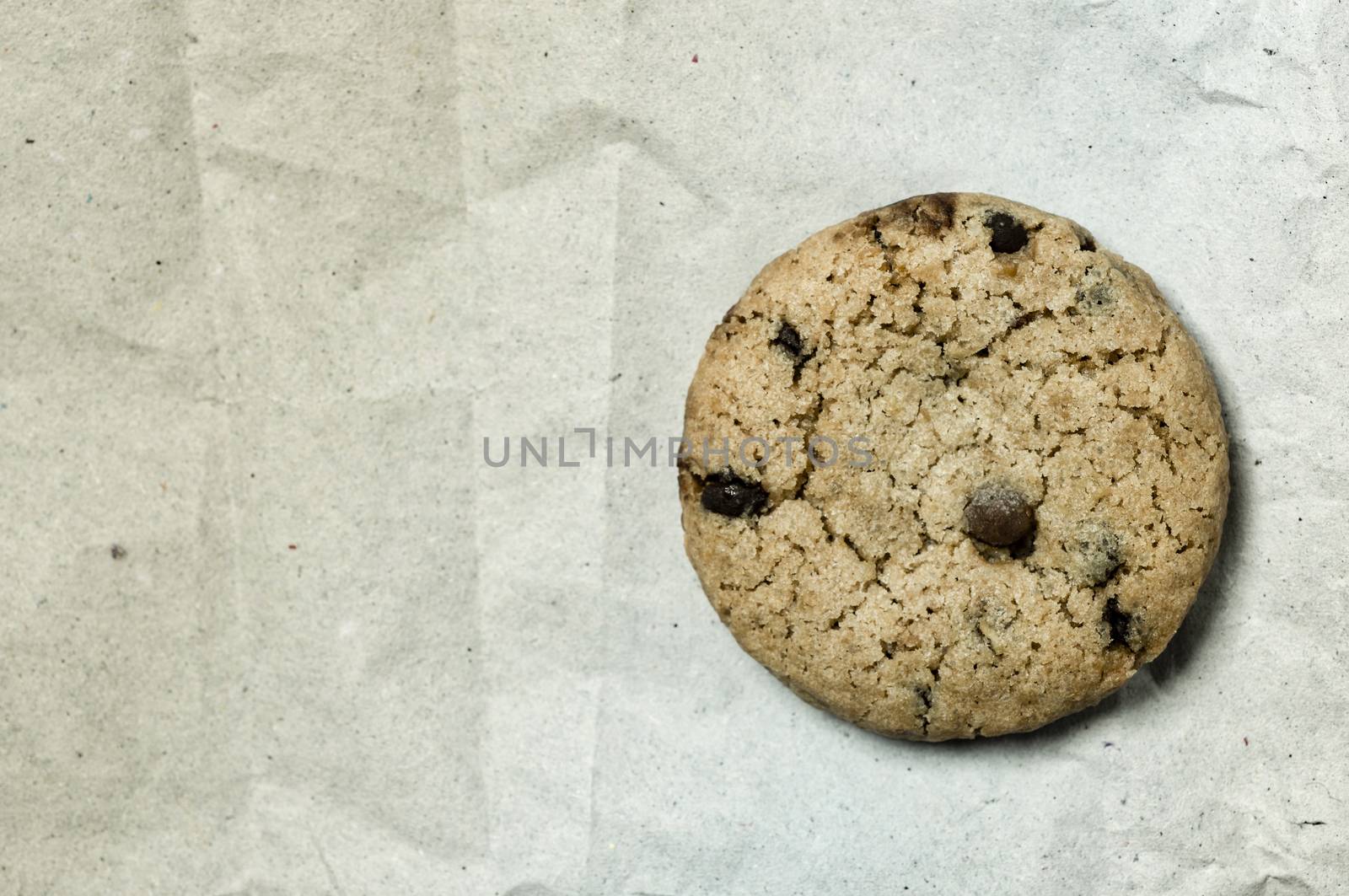 Macro shot of a danish cookie with chocolate drops over a white recycled paper background.