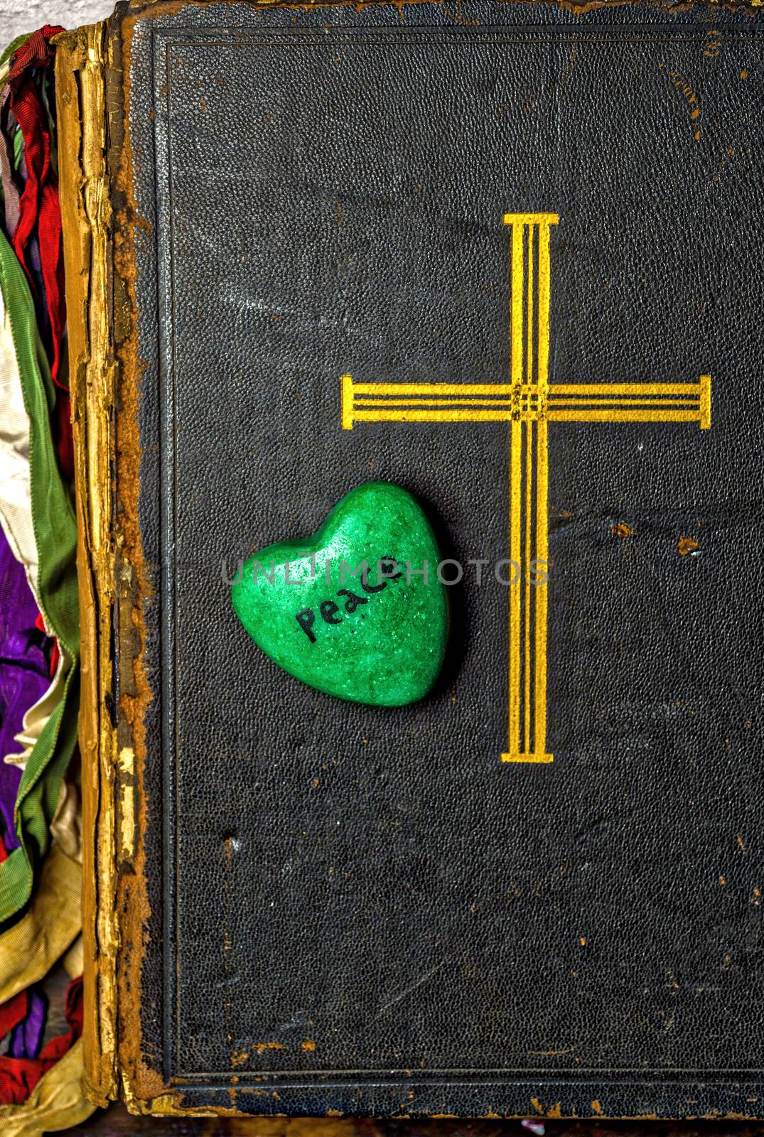 Catholic religion and peace concept represented by an old bible cover and a green - hope - heart.