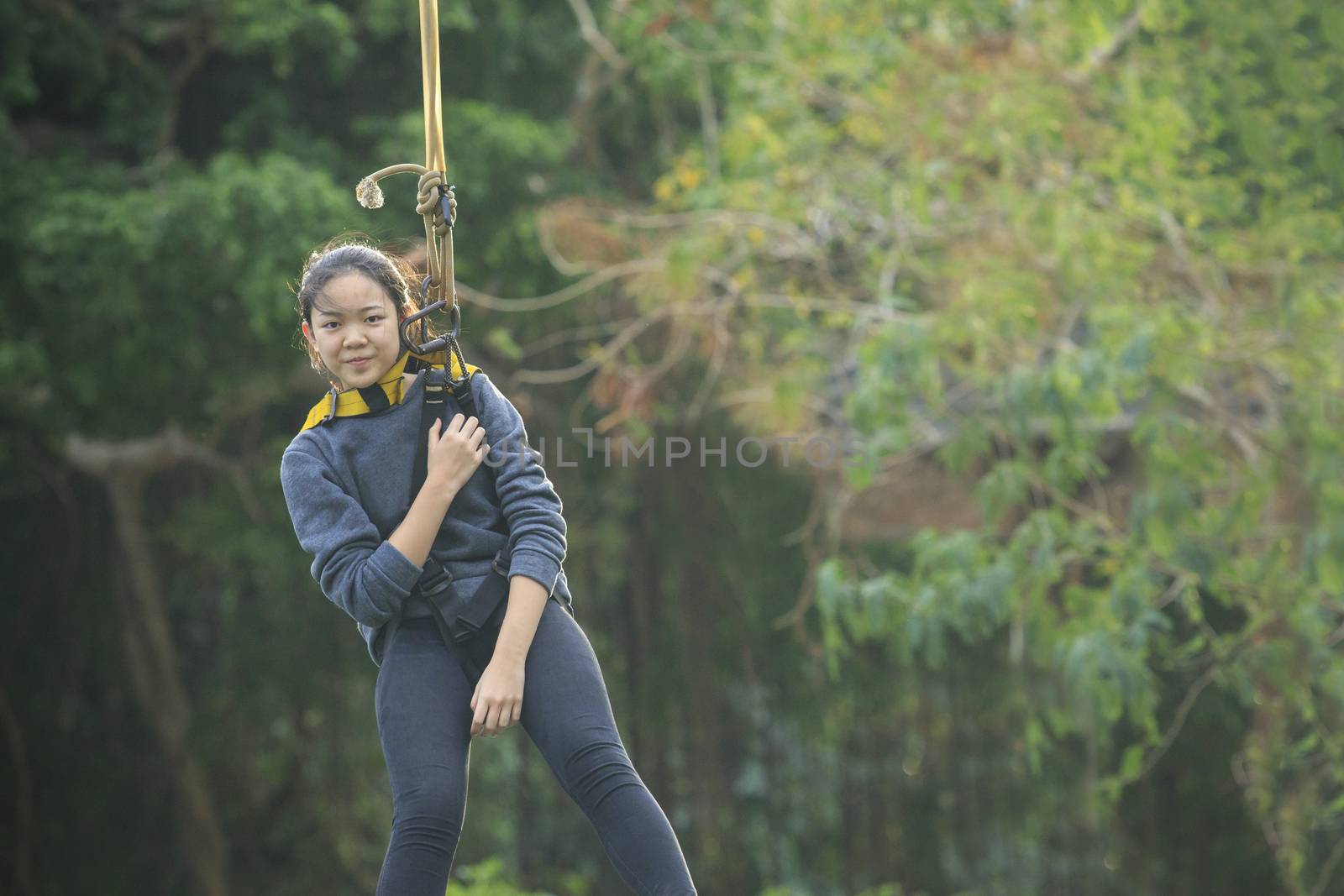 asian teen age  hanging on safety rope in outdoor adventure acti by khunaspix