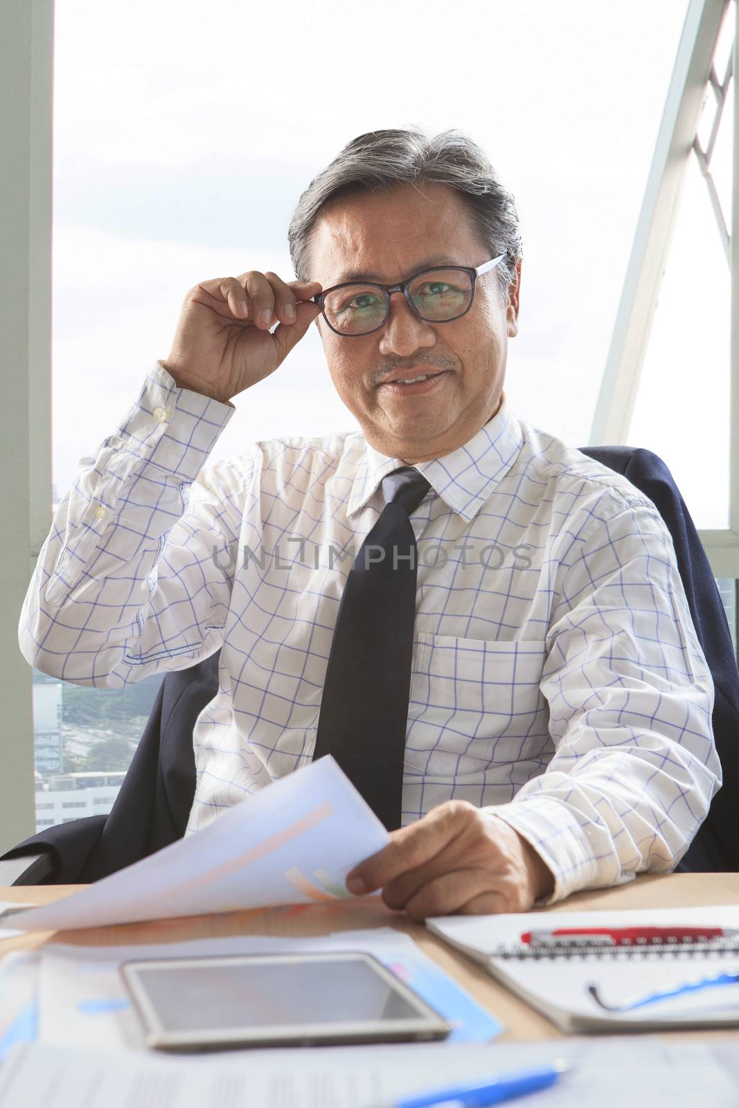 asian senior business man relaxing on working table by khunaspix
