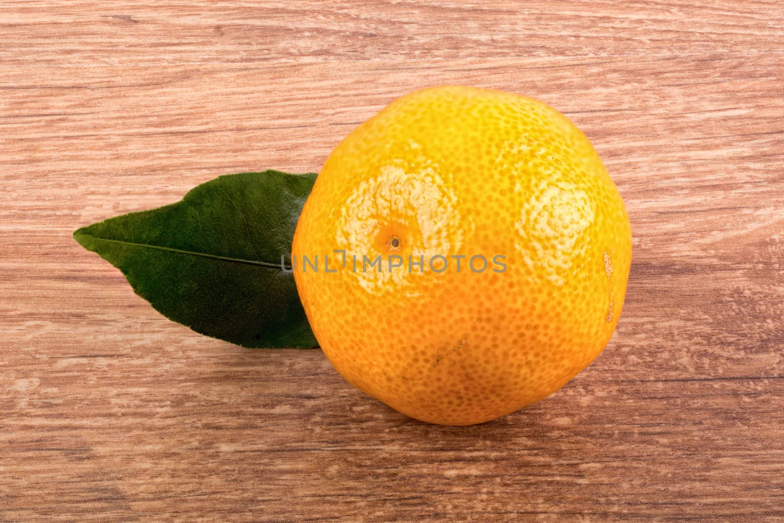 Mandarin with leafs over brown wooden background
