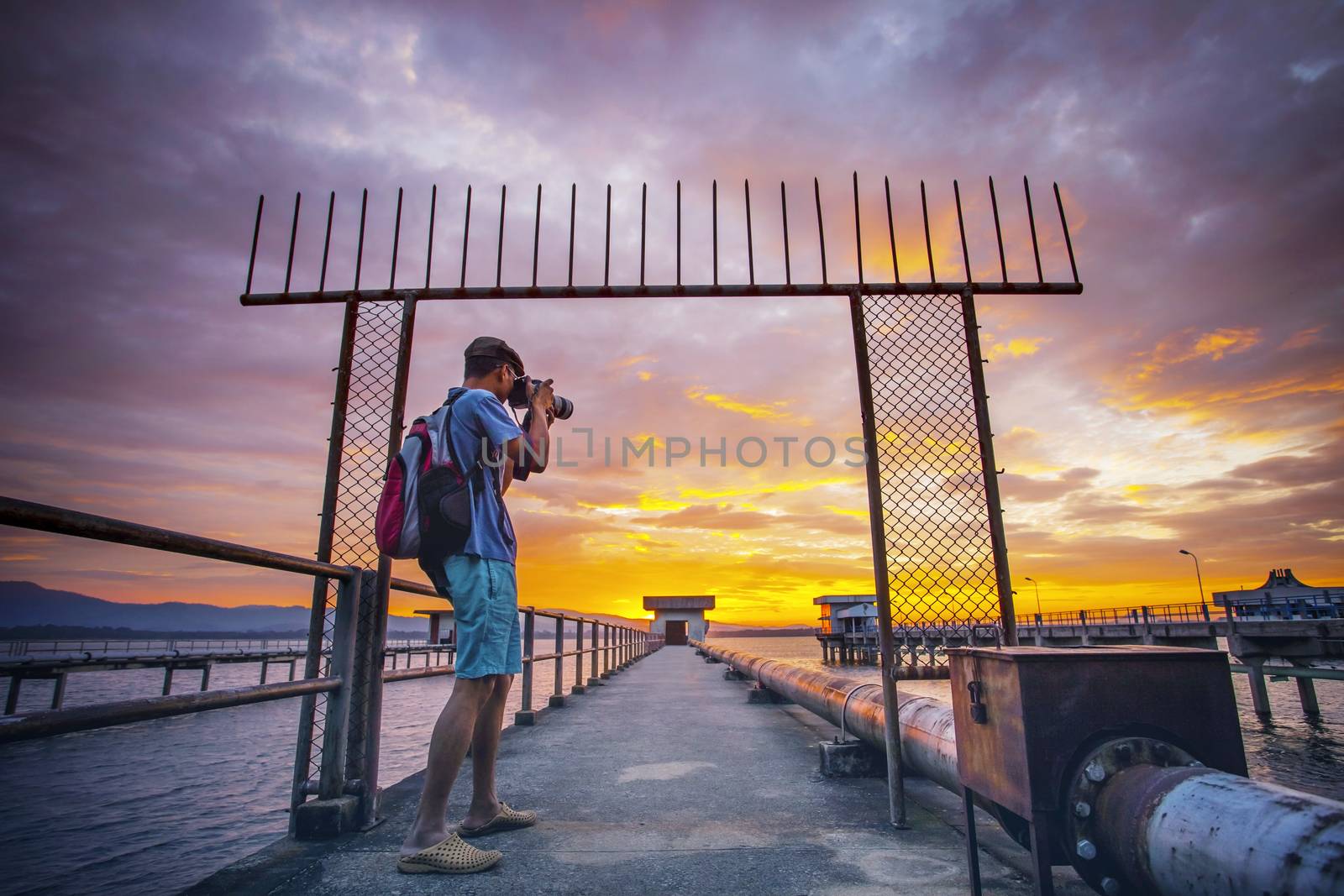 photographer taking a photograph  at water work station  and sun rising sky background