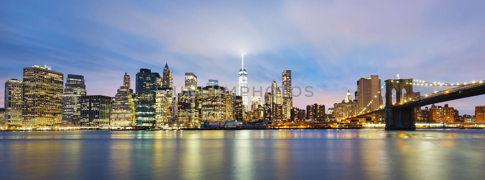 New York City Manhattan midtown at dusk with skyscrapers illuminated over east river