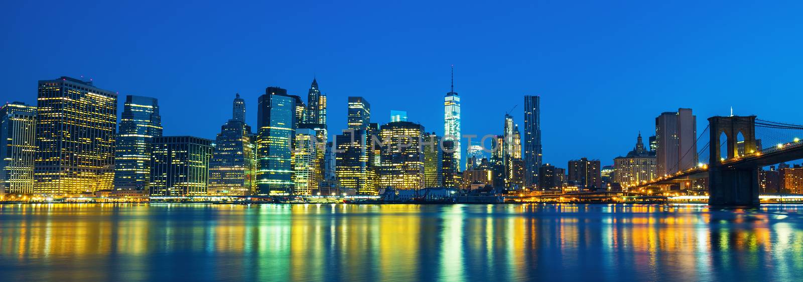 New York City Manhattan midtown at dusk with skyscrapers illuminated over east river