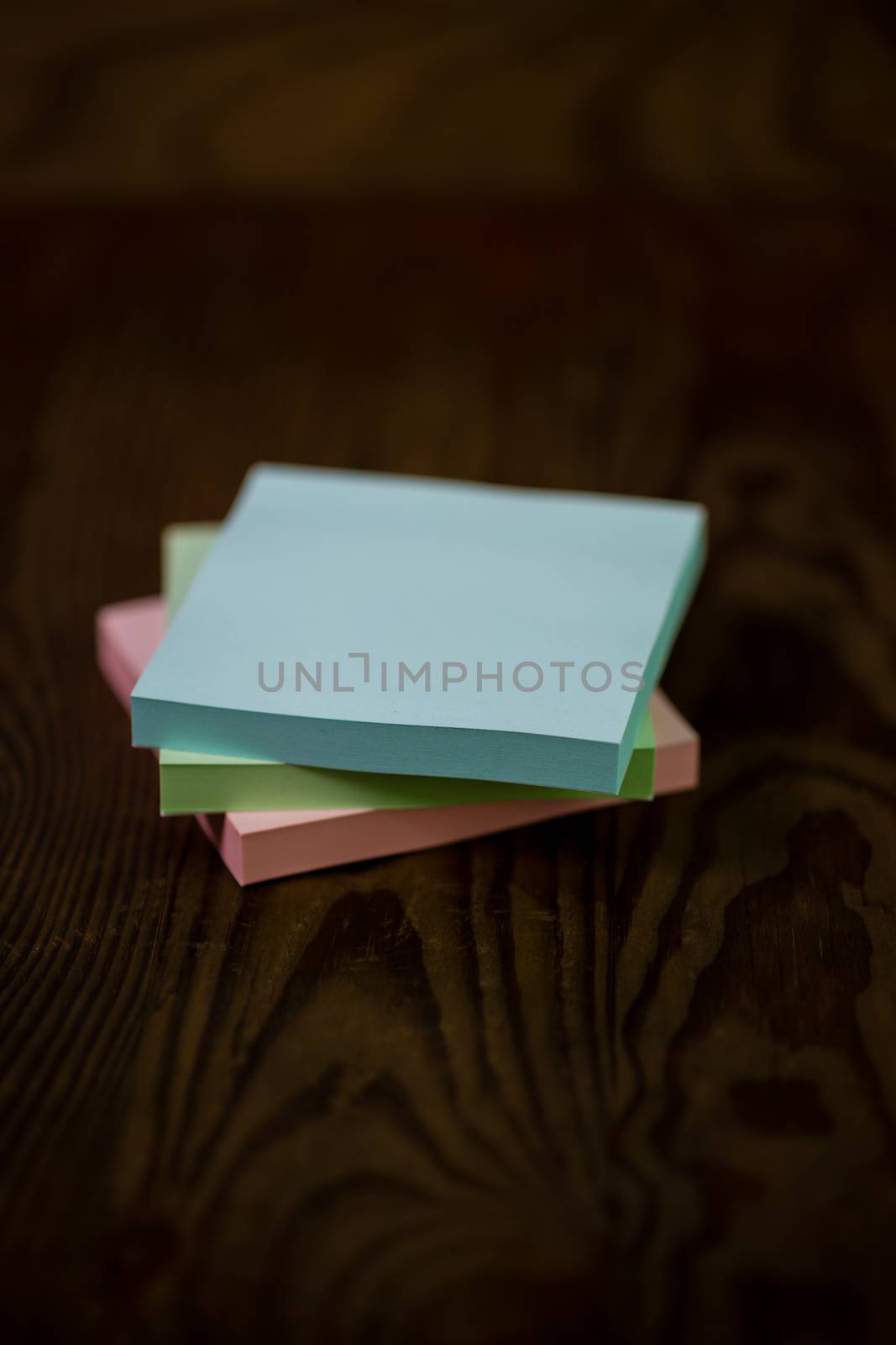 Stack of different colored notepads on ditressed wood background, shallow DOF