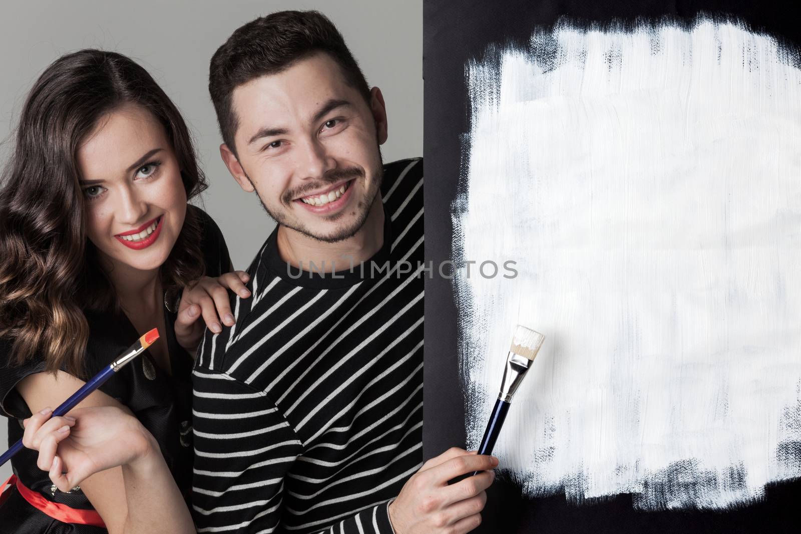 Couple with paint brushes and picture with white blank copy space