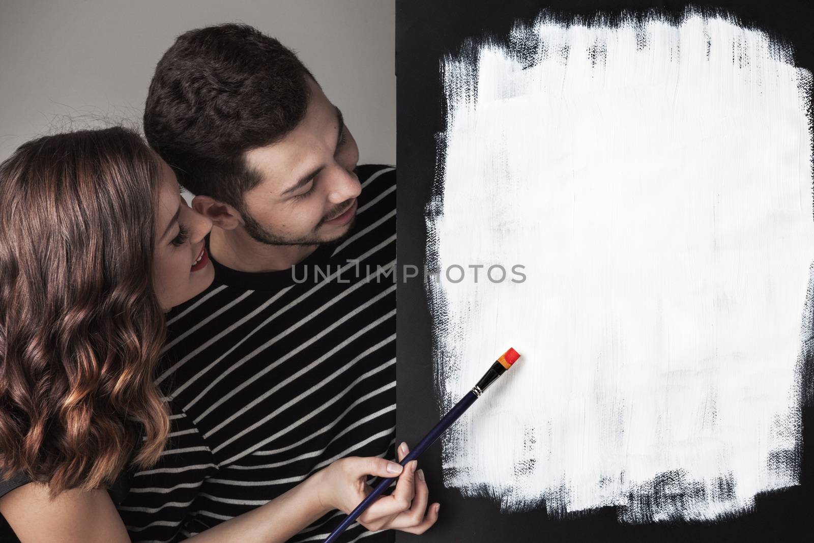 Couple with paint brushes and picture with white blank copy space