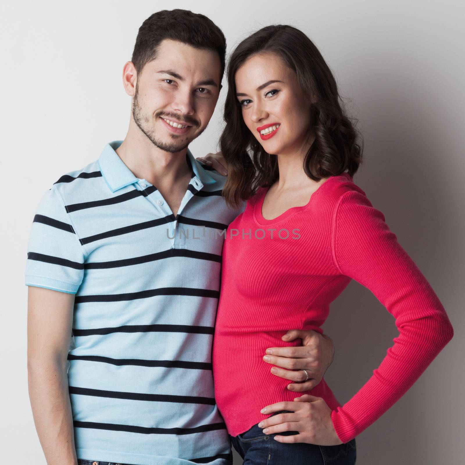 Young smiling couple standing on white background, studio shot