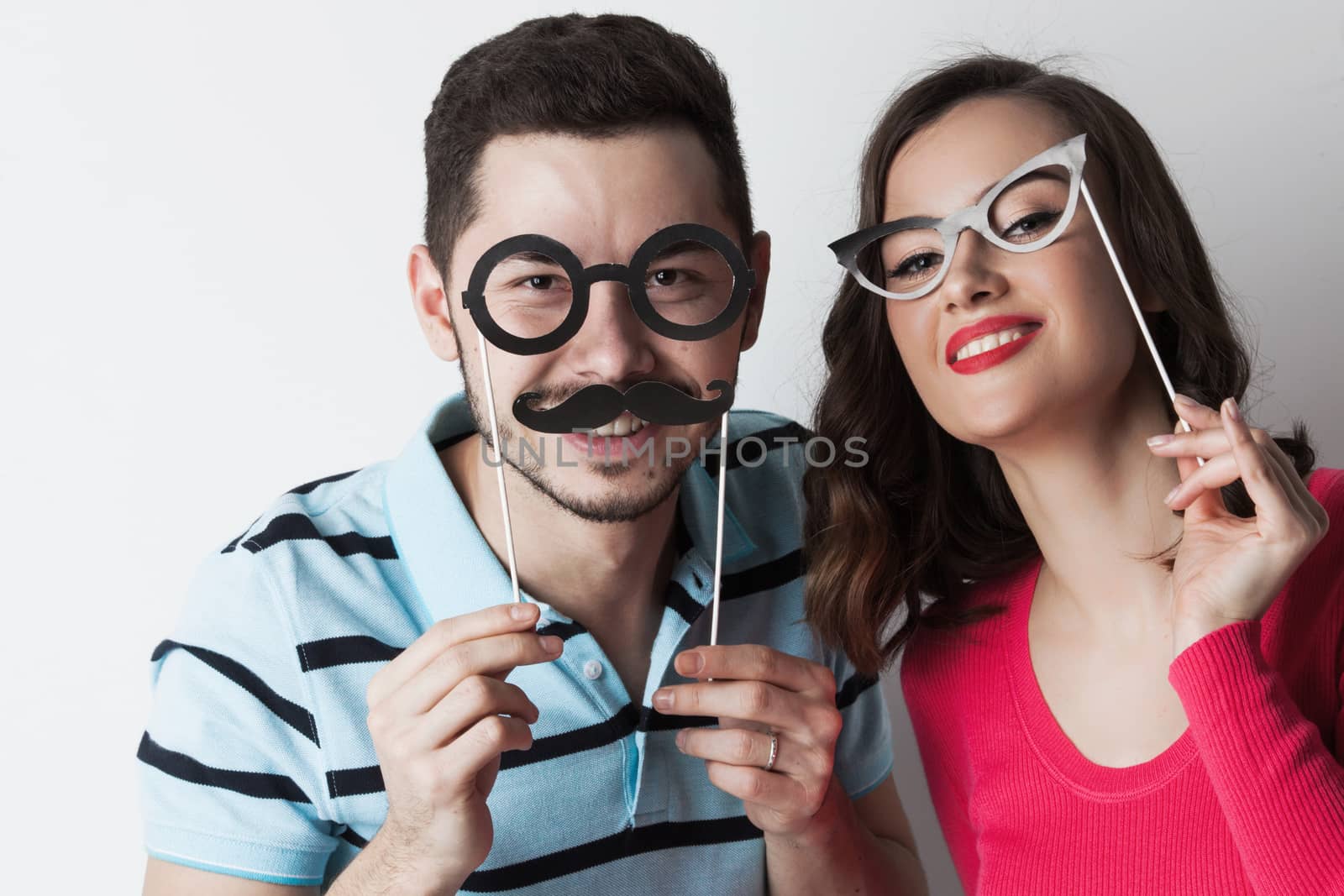 Funny couple holding party glasses and mustaches on sticks