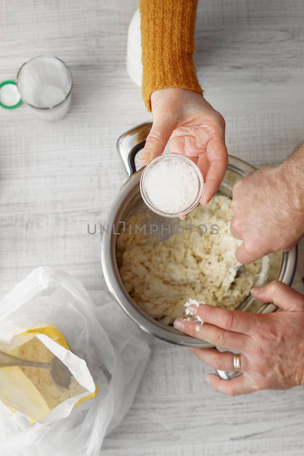 Man and woman makes the dough in the pan on the table vertical