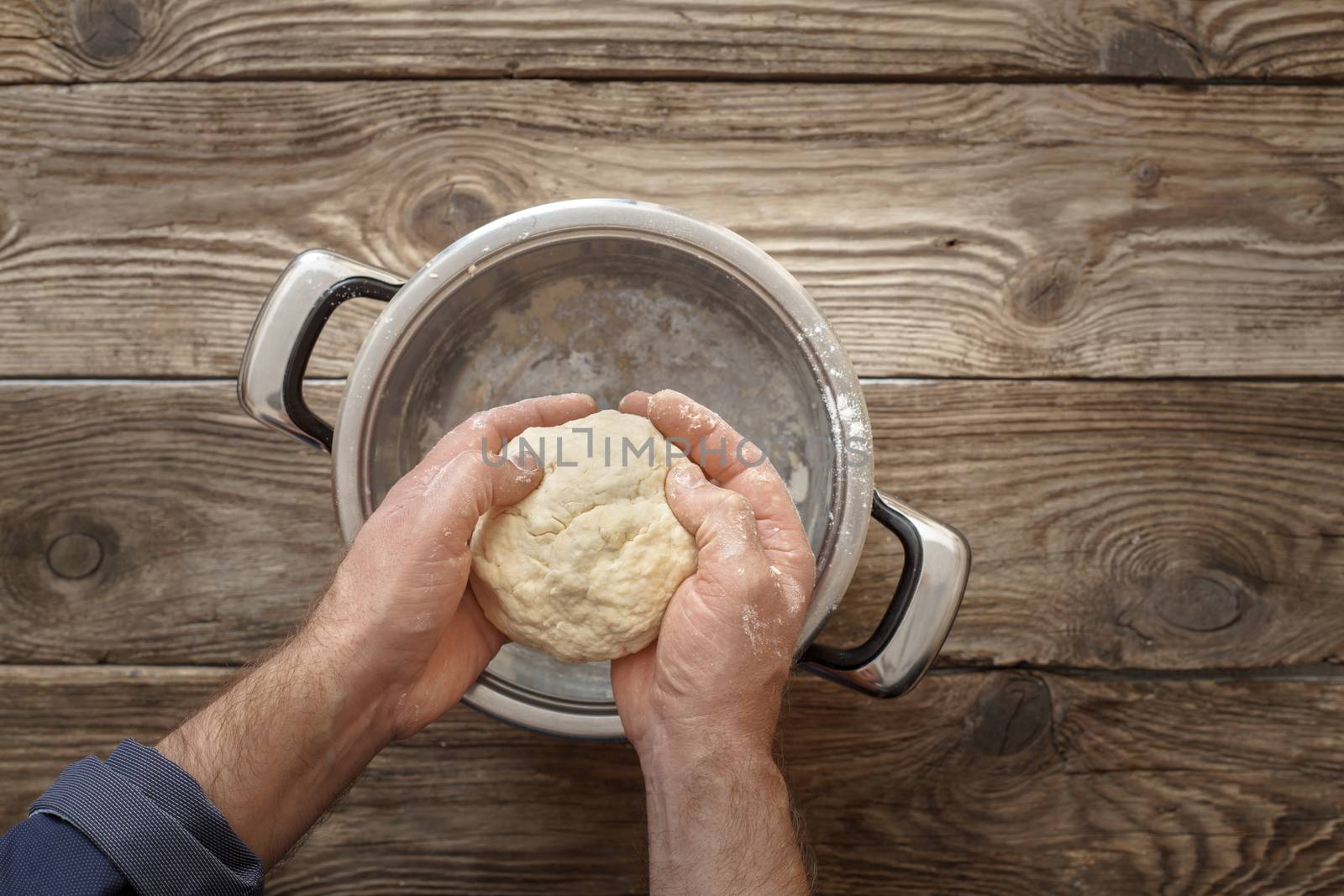 Man makes the dough in the pan horizontal