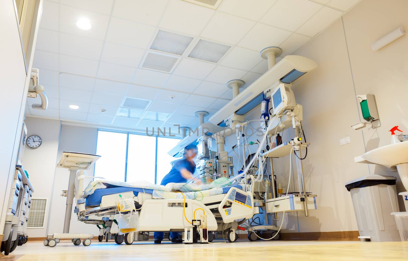 A hospital reanimation room with modern medical equipment and blurred patient and nurse or doctor figures.